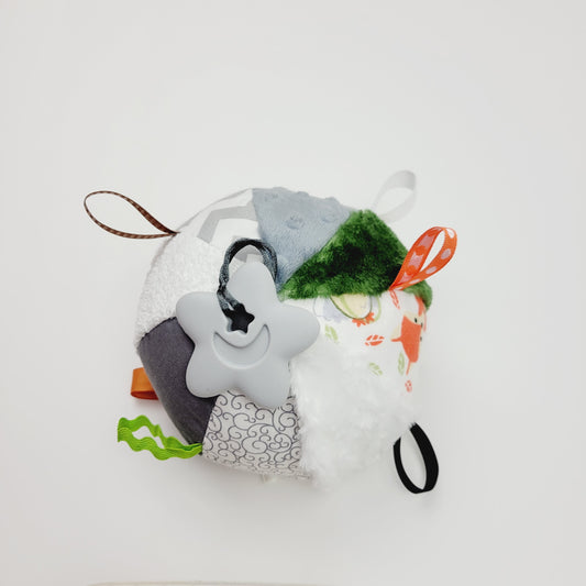 Ballon d'éveil pour bébé avec 8 tissus différents pour créer de la texture. On y retrouve un polar vert, du polar à pois gris, de la flanelle à chevron blanc et gris, de la ratine blanche, du coton blanc et gris, de la rosette blanche, de la flanelle imprimé avec des renards et des hiboux. Entre les différent tissu, il y a des petits rubans vert, orange, noir, blanc, brun et au bout d'un de ces rubans y est attaché un jouet de dentition en silicone gris en forme d'étoile avec une Lune à l'intérieur