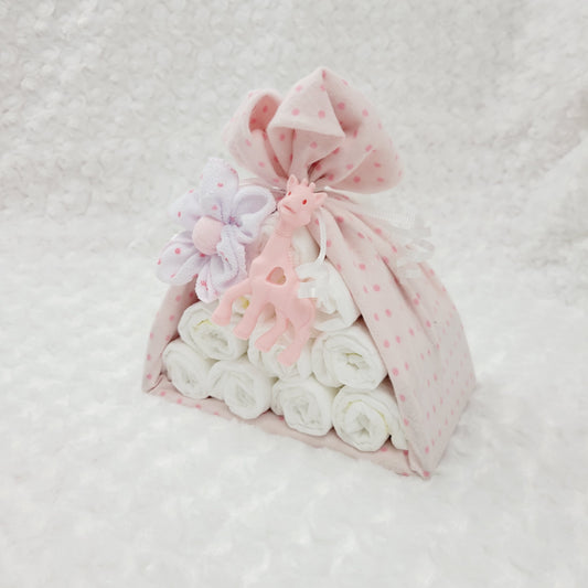 Ensemble cadeau baluchon avec une couverture en flanelle rose à pois. Contient 10 couches pour bébé de taille #2 ainsi que 2 débarbouillettes en disposées en fleur. Complété d'un jouet de dentition en silicone en forme de girafe rose.
