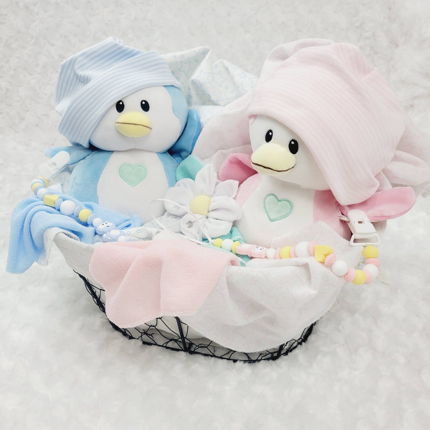 Ensemble cadeau pour babyshower de jumeaux garçon et fille. Un panier contenant des couvertures de flanelle 2 bonnets, des fleurs en débarbouillettes. complété de 2 attache-suce