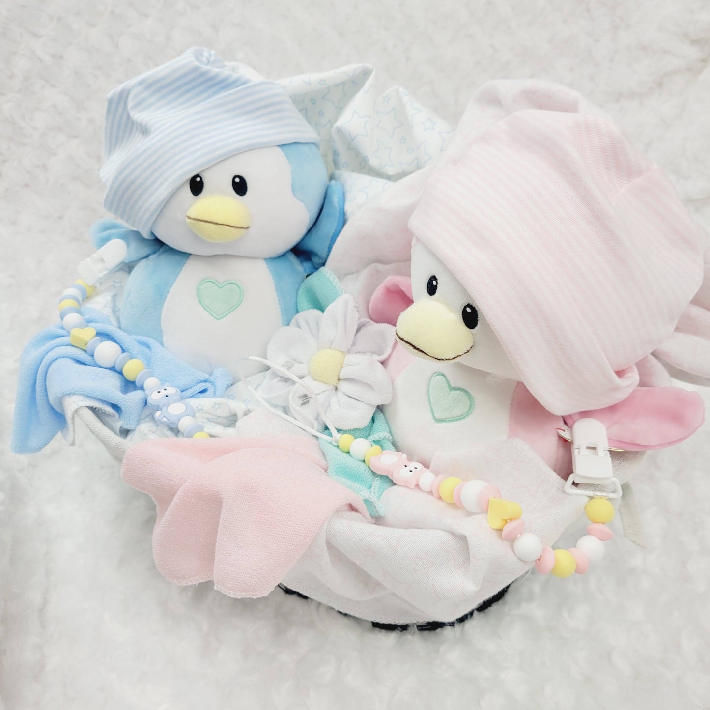 Ensemble cadeau pour babyshower de jumeaux garçon et fille. Un panier contenant des couvertures de flanelle 2 bonnets, des fleurs en débarbouillettes. complété de 2 attache-suce