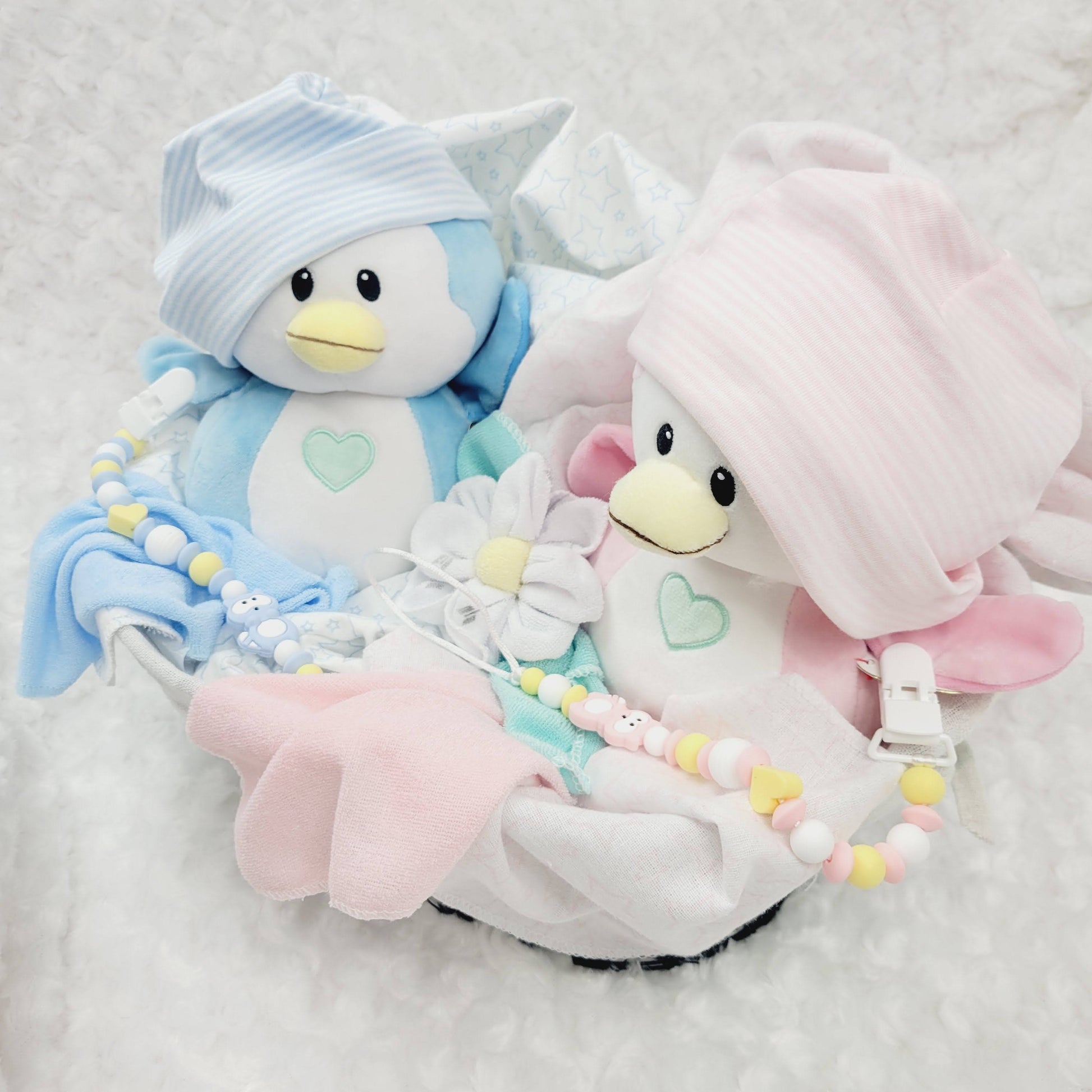 Ensemble cadeau pour babyshower de jumeaux garçon et fille. Un panier contenant des couvertures de flanelle 2 bonnets, des fleurs en débarbouillettes. complété de 2 attache-suce