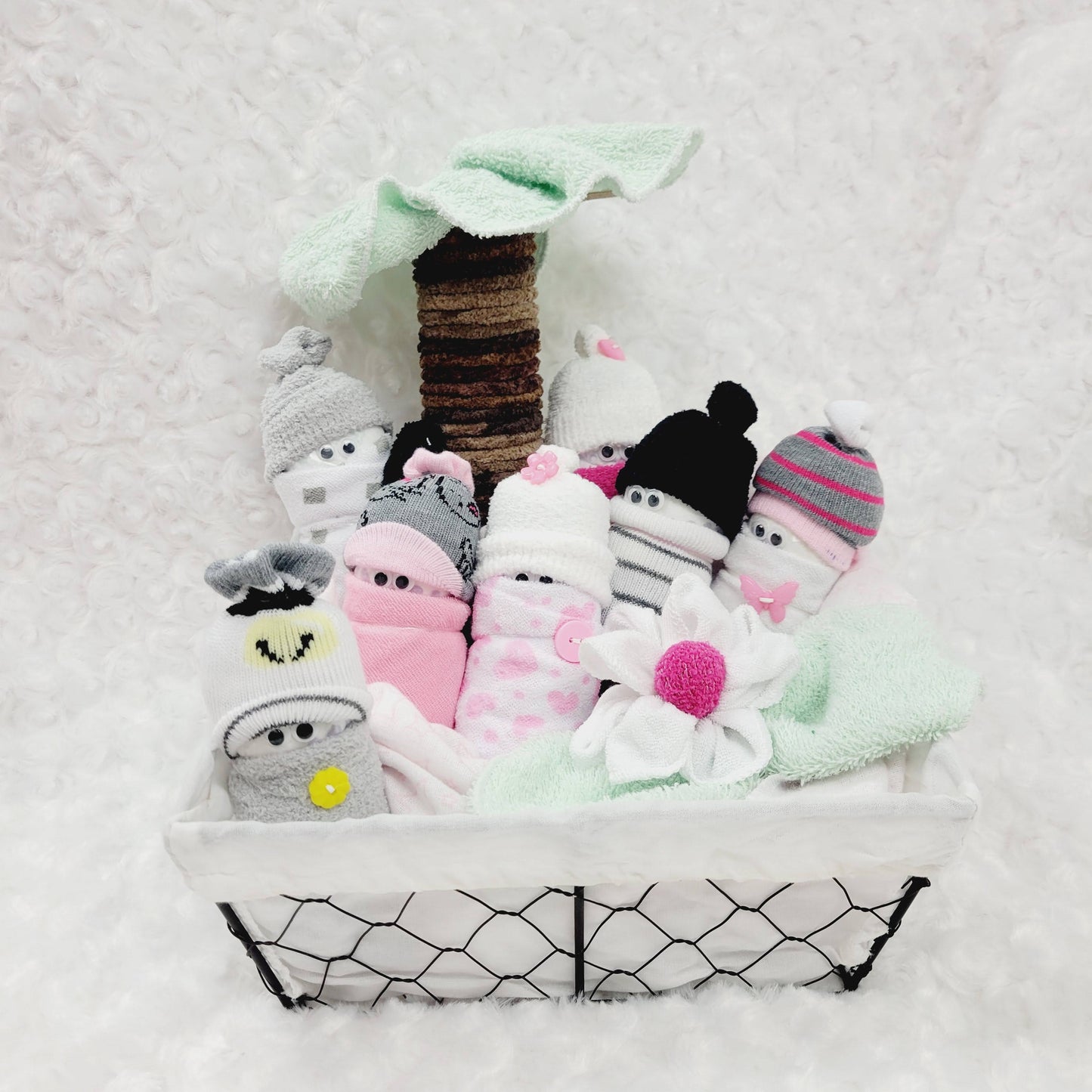 Ensemble cadeau pour babyshower avec des minions fait de couche pour bébé de taille #2 habiller avec des bas de coton et des débarbouillettes, le tout dans un panier avec un palmier fait aussi de débarbouillettes.