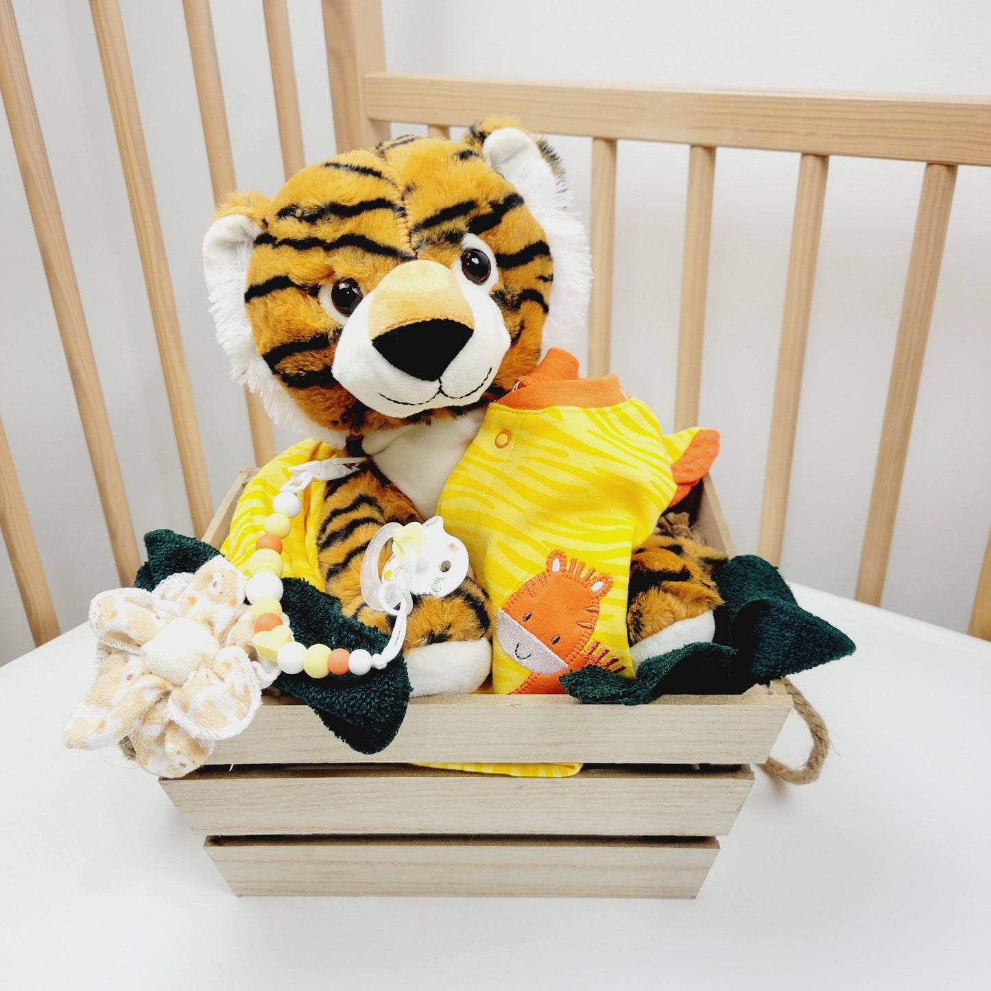 Ensemble cadeau pour babyshower pour bébé garçon. Panier contenant un toutou de tigre, un pyjamas jaune orange avec un tigre, un attache-suce et la suce ainsi que des débarbouillettes.