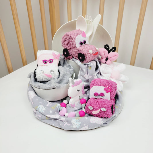 Ensemble cadeau pour babyshower de bébé fille. Contenat un couverture de flanelle grise avec des cigognes, des débarbouillettes disposées en forme de petites autos, papillons et fleur. Complété d'une assiette en plastique, un bol, un verre et les ustensiles. Retrouvez aussi un jouet de dentition avec un licorne en silicone.