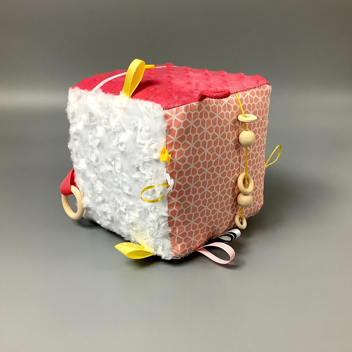 Cube d'éveil pour enfant Fait en coton avec rubans et petits accessoires de bois. Le cube fait du bruit lorsqu'il est agité. Ce produit unique est fait au Québec.