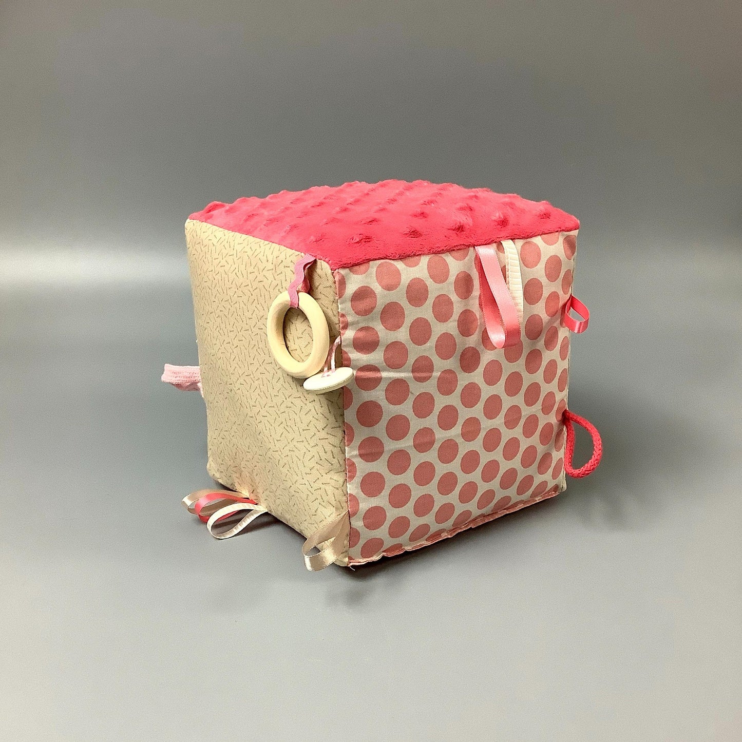 Cube d'éveil pour enfant  Fait en coton avec rubans et petits accessoires de bois. Le cube fait du bruit lorsqu'il est agité.  Ce produit unique est fait au Québec.