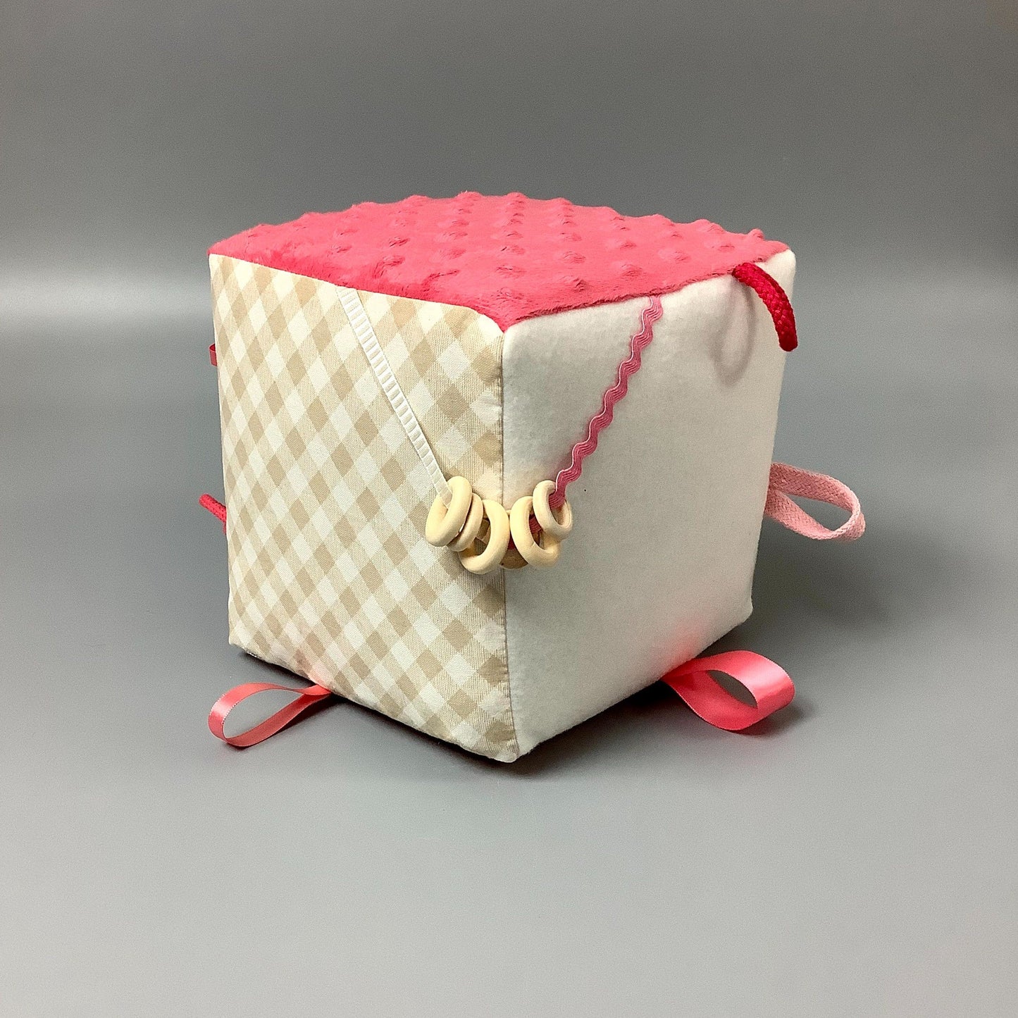 Cube d'éveil pour enfant  Fait en coton avec rubans et petits accessoires de bois. Le cube fait du bruit lorsqu'il est agité.  Ce produit unique est fait au Québec.