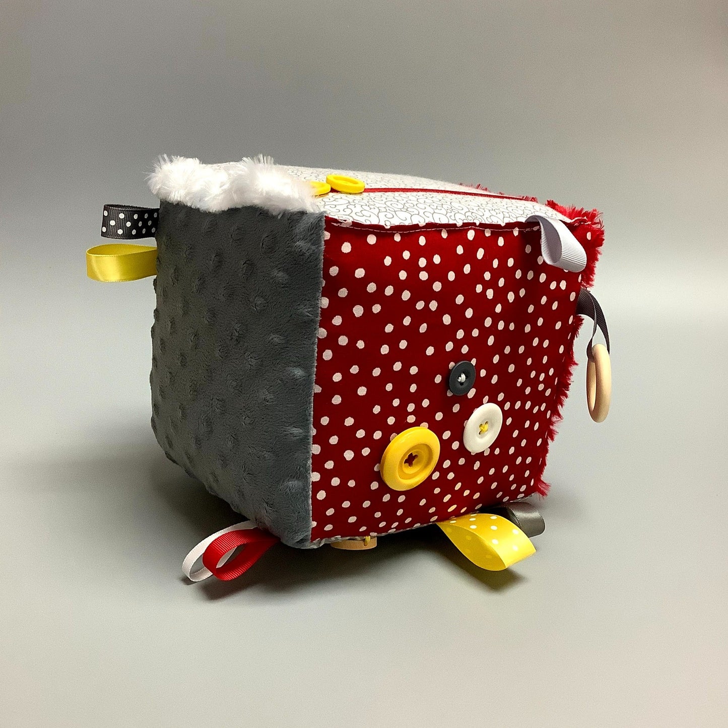 Cube d'éveil pour enfant Fait en coton avec rubans et petits accessoires de bois. Le cube fait du bruit lorsqu'il est agité. Ce produit unique est fait au Québec.