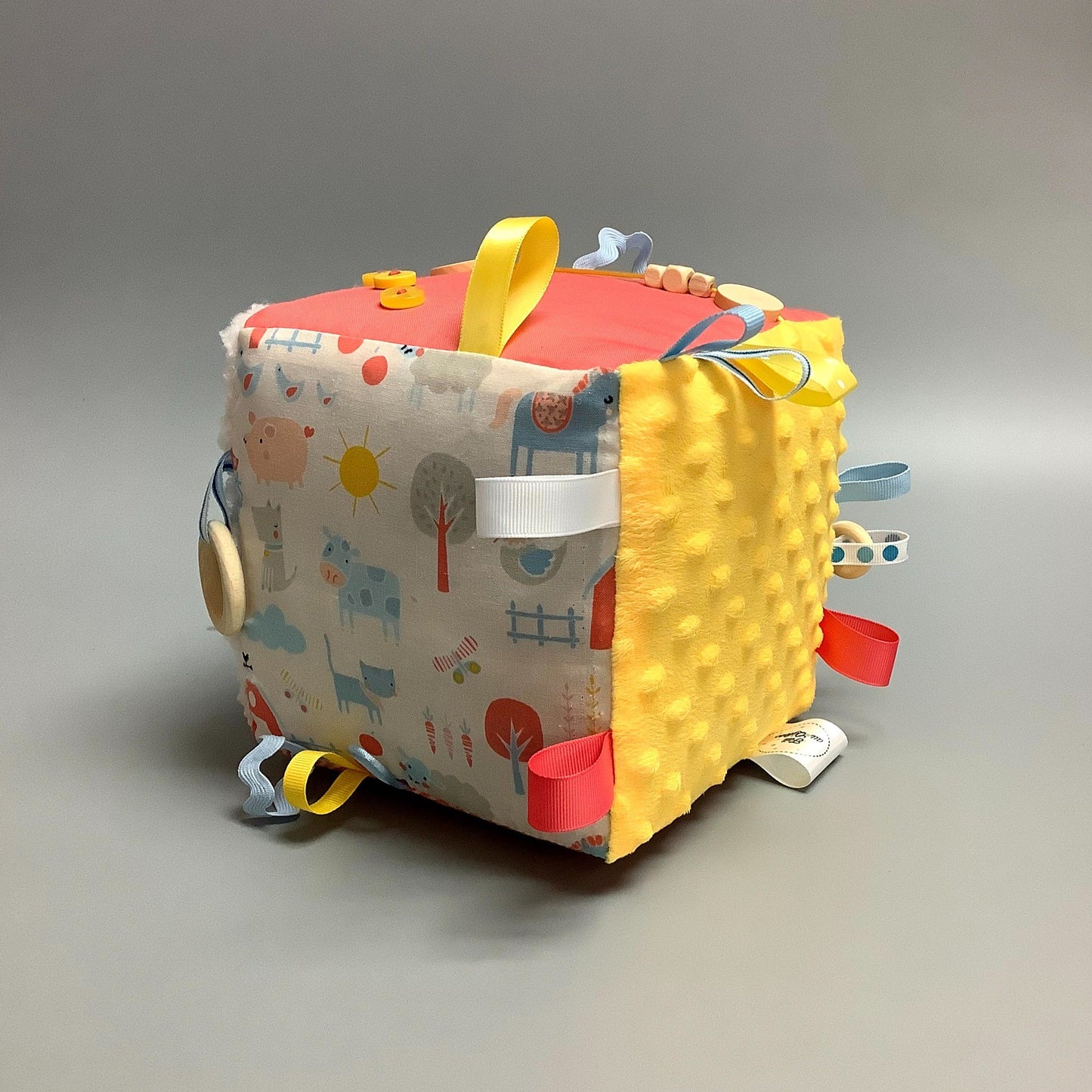 Cube d'éveil pour enfant Fait en coton avec rubans et petits accessoires de bois. Le cube fait du bruit lorsqu'il est agité. Ce produit unique est fait au Québec.