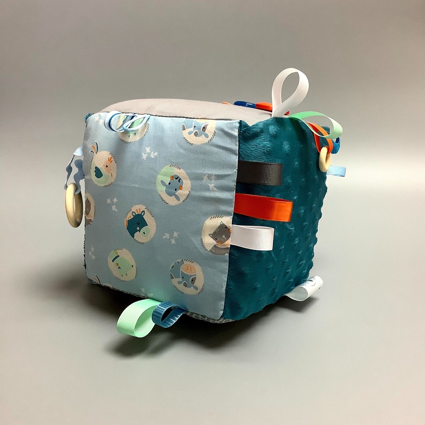 Cube d'éveil pour enfant Fait en coton avec rubans et petits accessoires de bois. Le cube fait du bruit lorsqu'il est agité. Ce produit unique est fait au Québec.