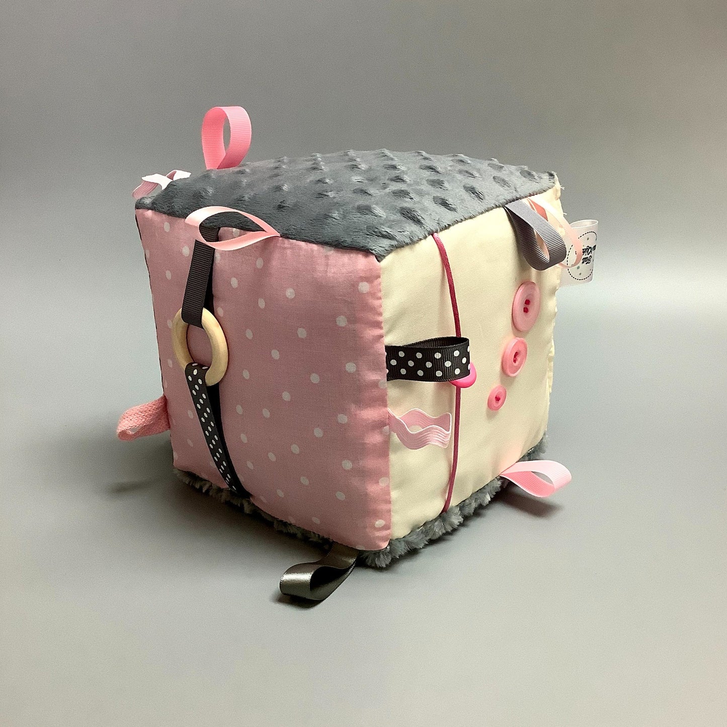 Cube d'éveil pour enfant  Fait en coton avec rubans et petits accessoires de bois. Le cube fait du bruit lorsqu'il est agité.  Ce produit unique est fait au Québec.