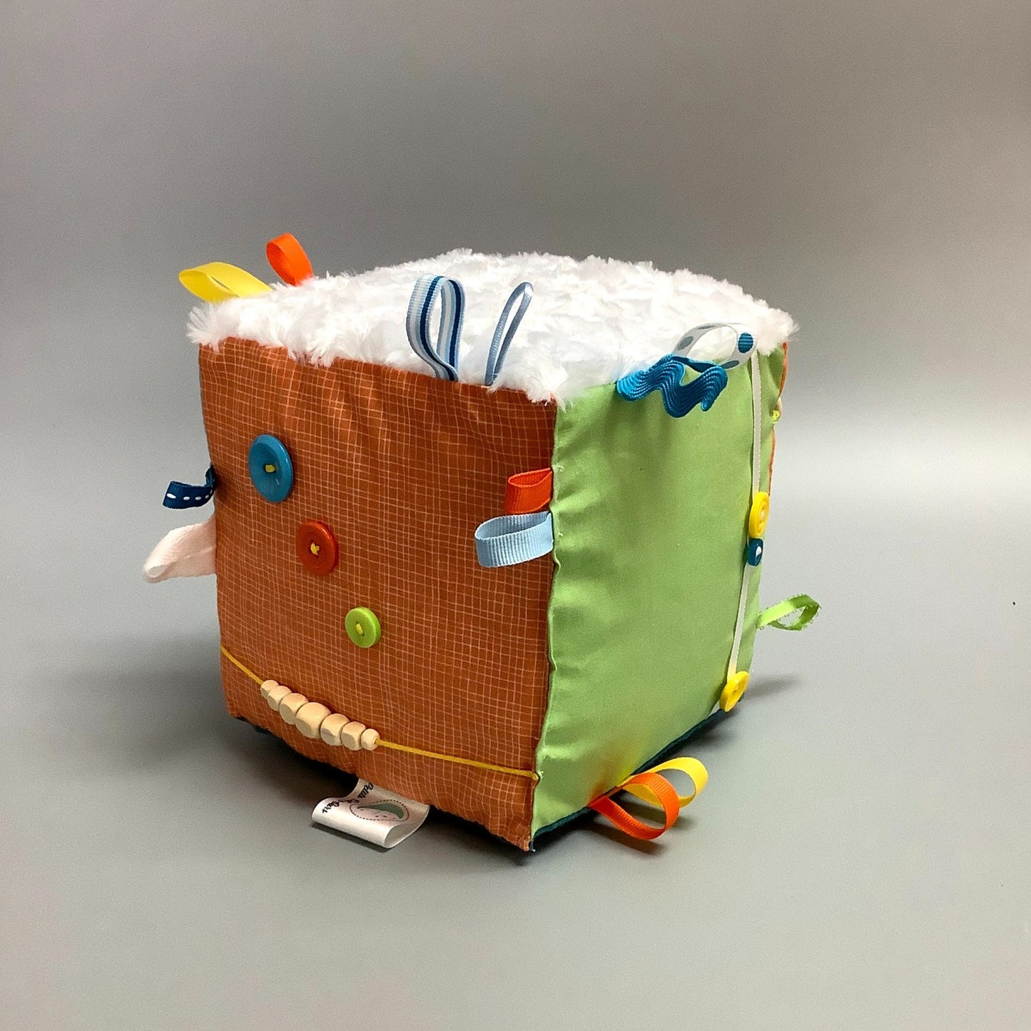 Cube d'éveil pour enfant  Fait en coton avec rubans et petits accessoires de bois. Le cube fait du bruit lorsqu'il est agité.  Ce produit unique est fait au Québec.