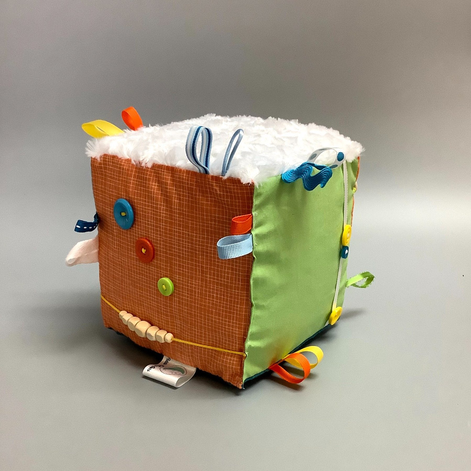 Cube d'éveil pour enfant  Fait en coton avec rubans et petits accessoires de bois. Le cube fait du bruit lorsqu'il est agité.  Ce produit unique est fait au Québec.