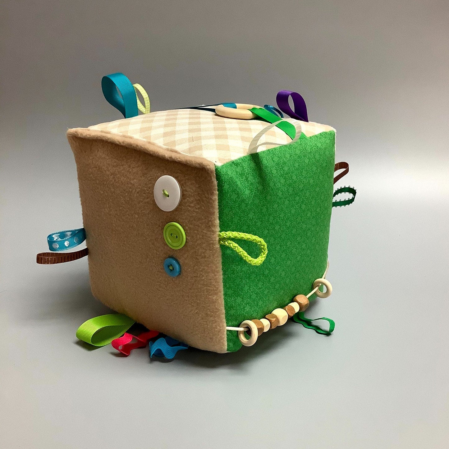 Cube d'éveil pour enfant Fait en coton avec rubans et petits accessoires de bois. Le cube fait du bruit lorsqu'il est agité. Ce produit unique est fait au Québec.