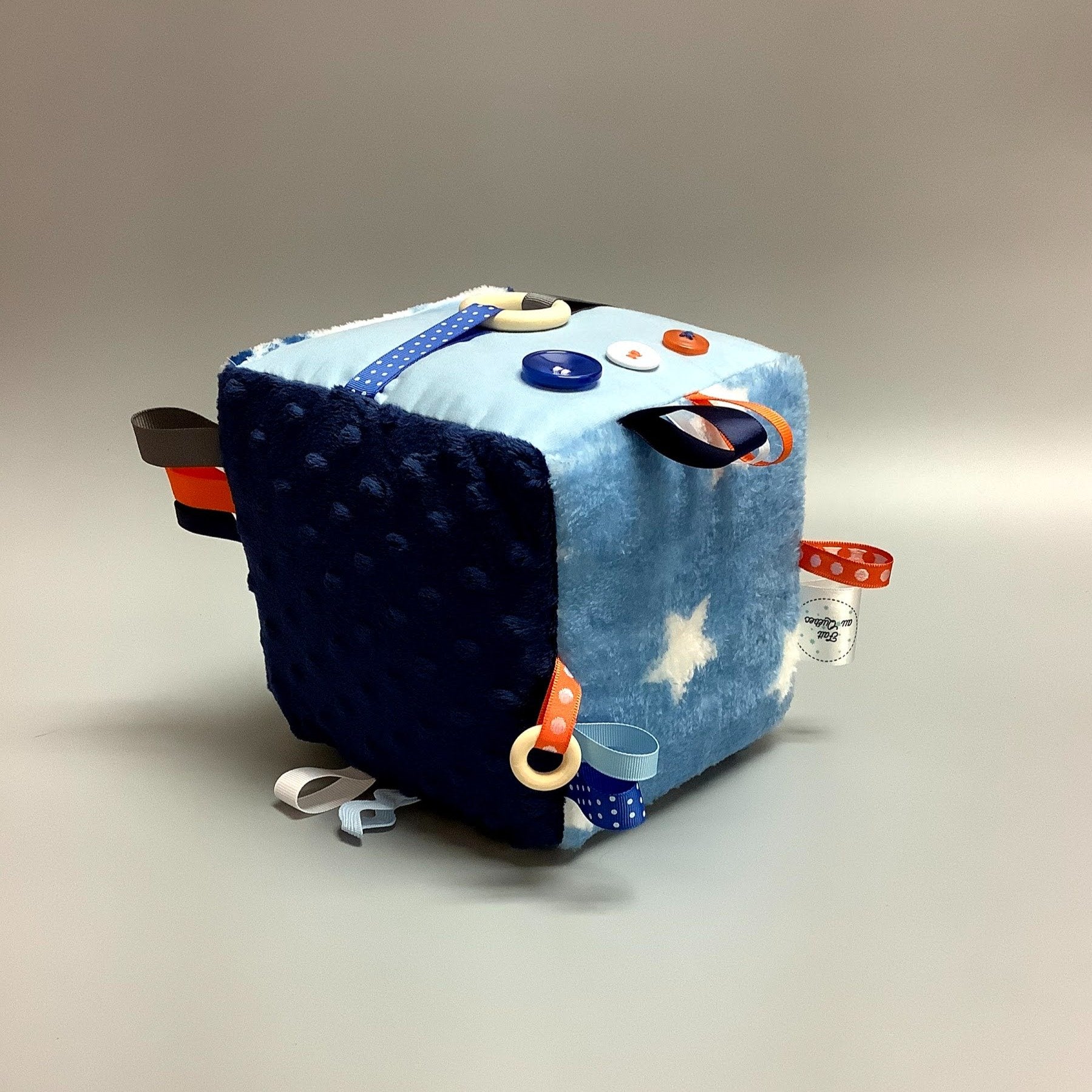 Cube d'éveil pour enfant  Fait en coton avec rubans et petits accessoires de bois. Le cube fait du bruit lorsqu'il est agité.  Ce produit unique est fait au Québec.