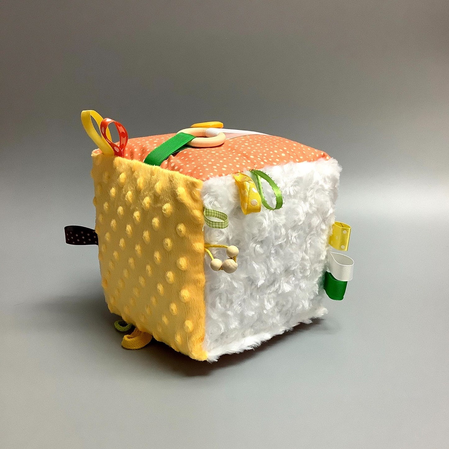 Cube d'éveil pour enfant Fait en coton avec rubans et petits accessoires de bois. Le cube fait du bruit lorsqu'il est agité. Ce produit unique est fait au Québec.