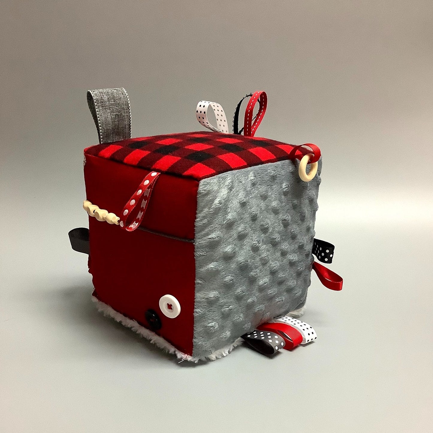 Cube d'éveil pour enfant  Fait en coton avec rubans et petits accessoires de bois. Le cube fait du bruit lorsqu'il est agité.  Ce produit unique est fait au Québec.