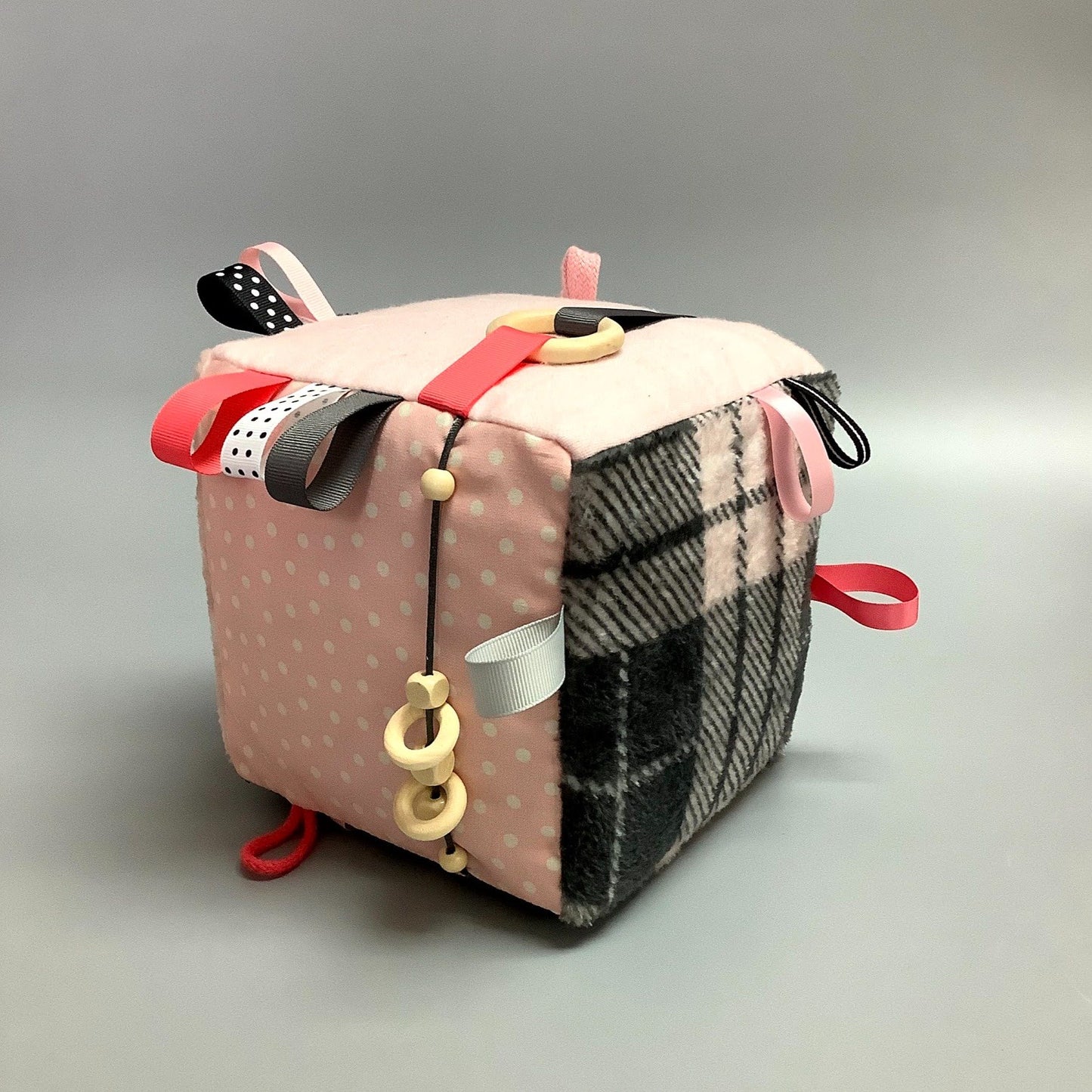 Cube d'éveil pour enfant  Fait en coton avec rubans et petits accessoires de bois. Le cube fait du bruit lorsqu'il est agité.  Ce produit unique est fait au Québec.