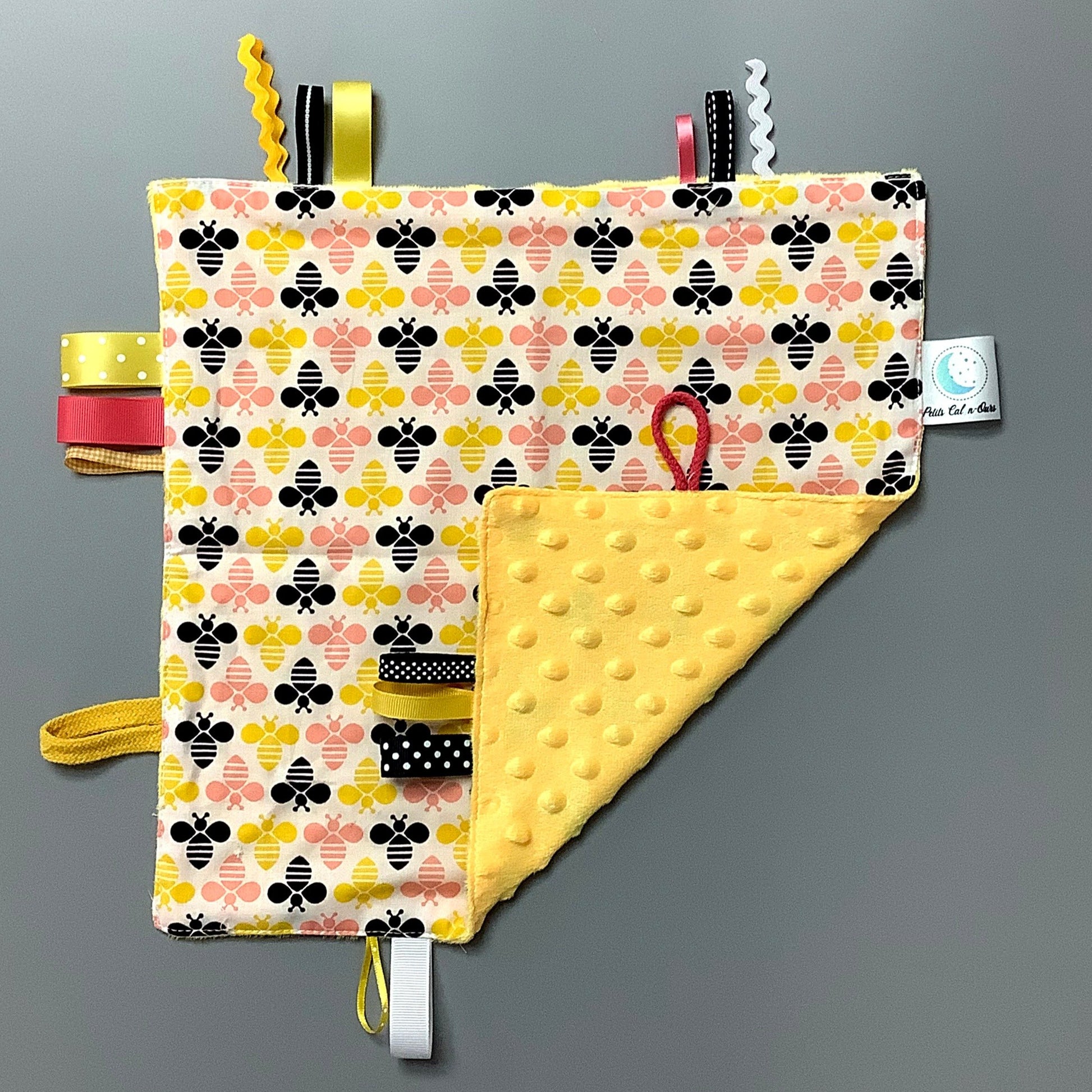 Doudou Calyn  pour les enfants   Fait en coton et avec du polars flanelle (notre tissu à doudou super doux), avec différents rubans.   Chaque doudou est fait au Québec et est unique.   Doudou : 12'' x 12''