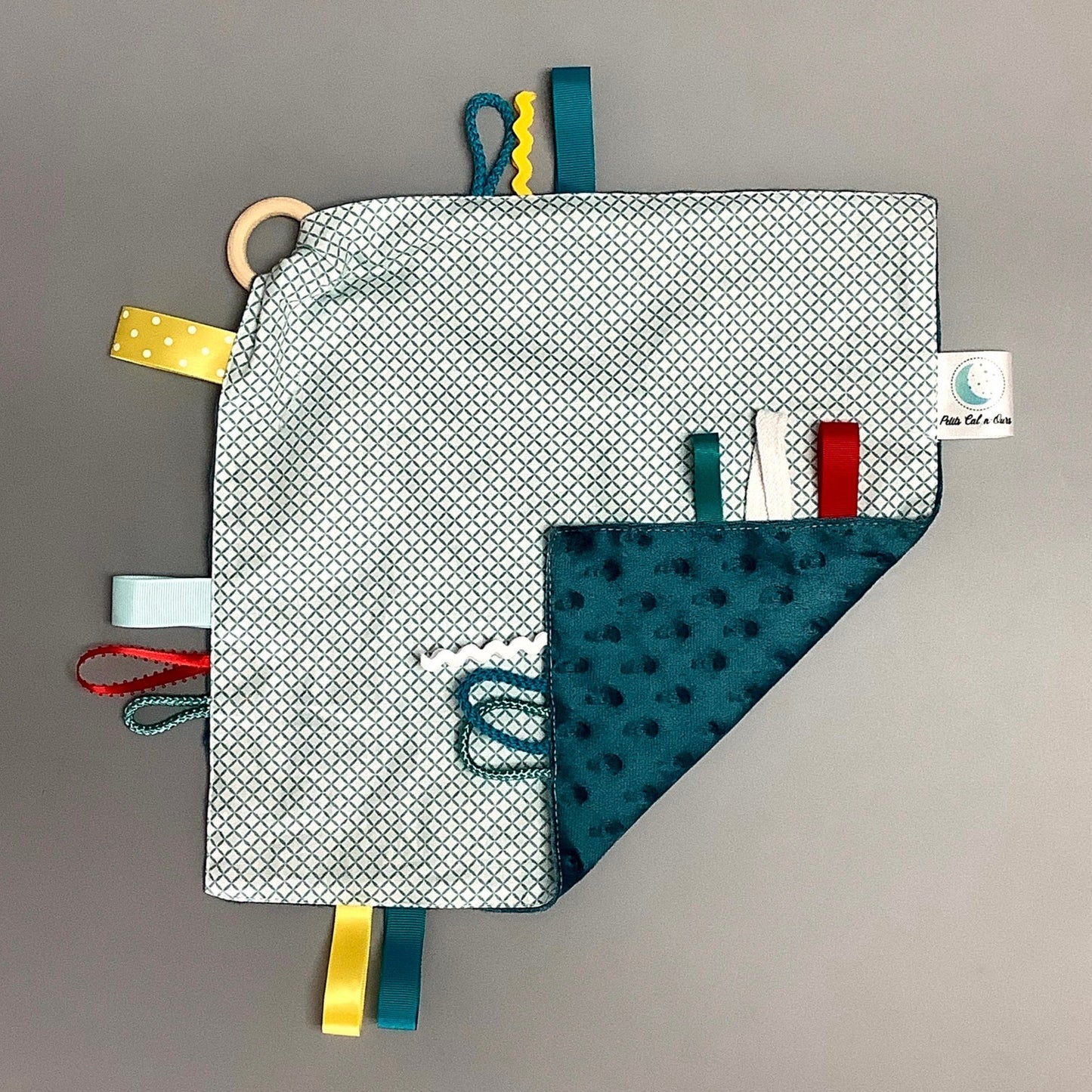 Doudou Calyn pour les enfants Fait en coton et avec du polars flanelle (notre tissu à doudou super doux), avec différents rubans. Chaque doudou est fait au Québec et est unique. Doudou : 12'' x 12''