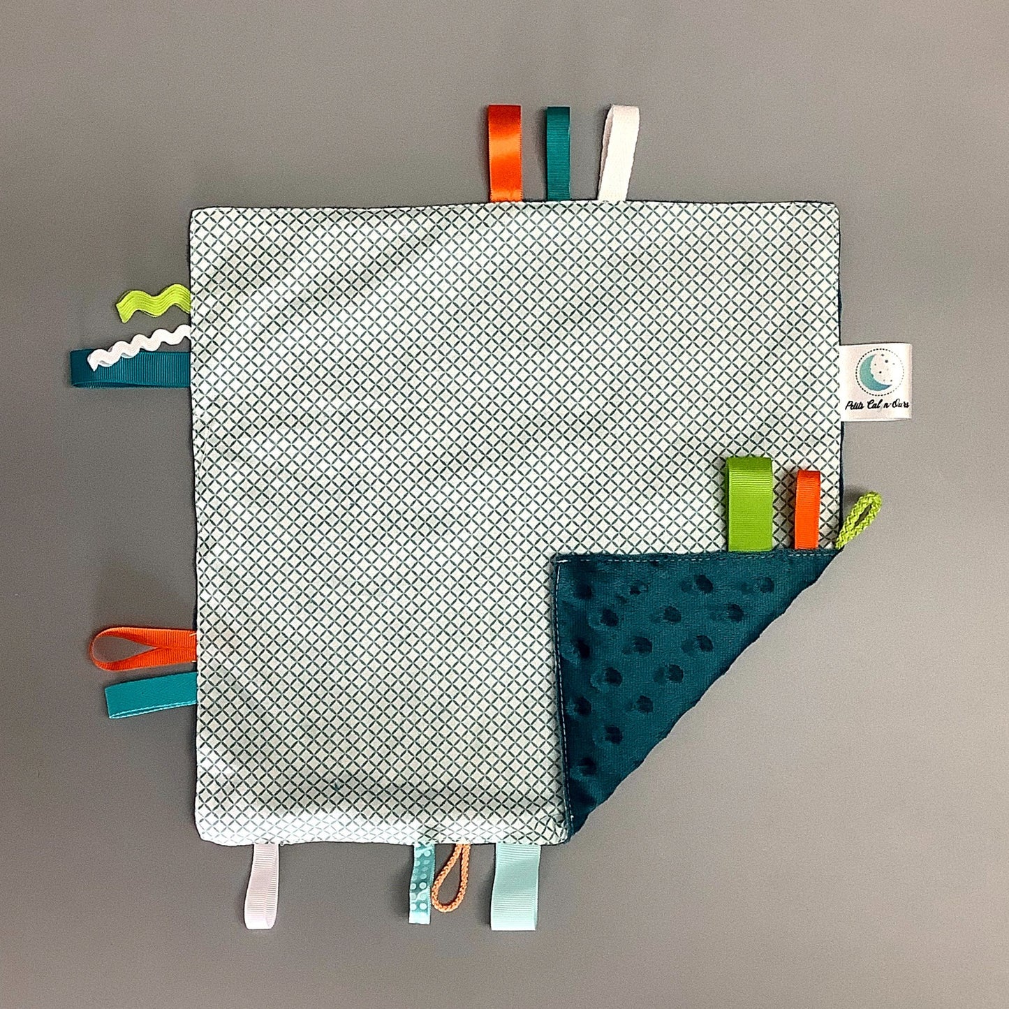 Doudou Calyn pour les enfants Fait en coton et avec du polars flanelle (notre tissu à doudou super doux), avec différents rubans. Chaque doudou est fait au Québec et est unique. Doudou : 12'' x 12''