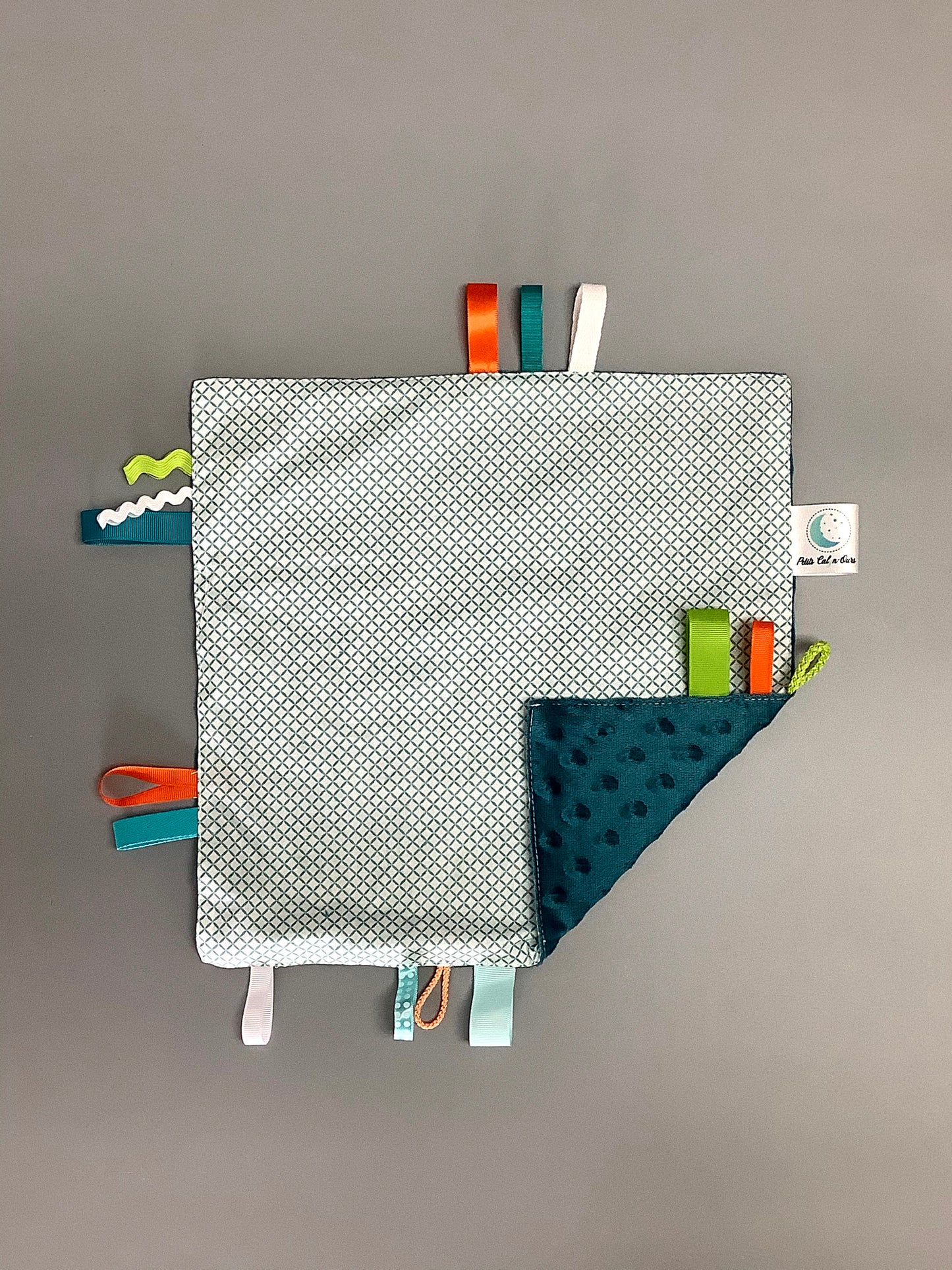 Doudou Calyn pour les enfants Fait en coton et avec du polars flanelle (notre tissu à doudou super doux), avec différents rubans. Chaque doudou est fait au Québec et est unique. Doudou : 12'' x 12''