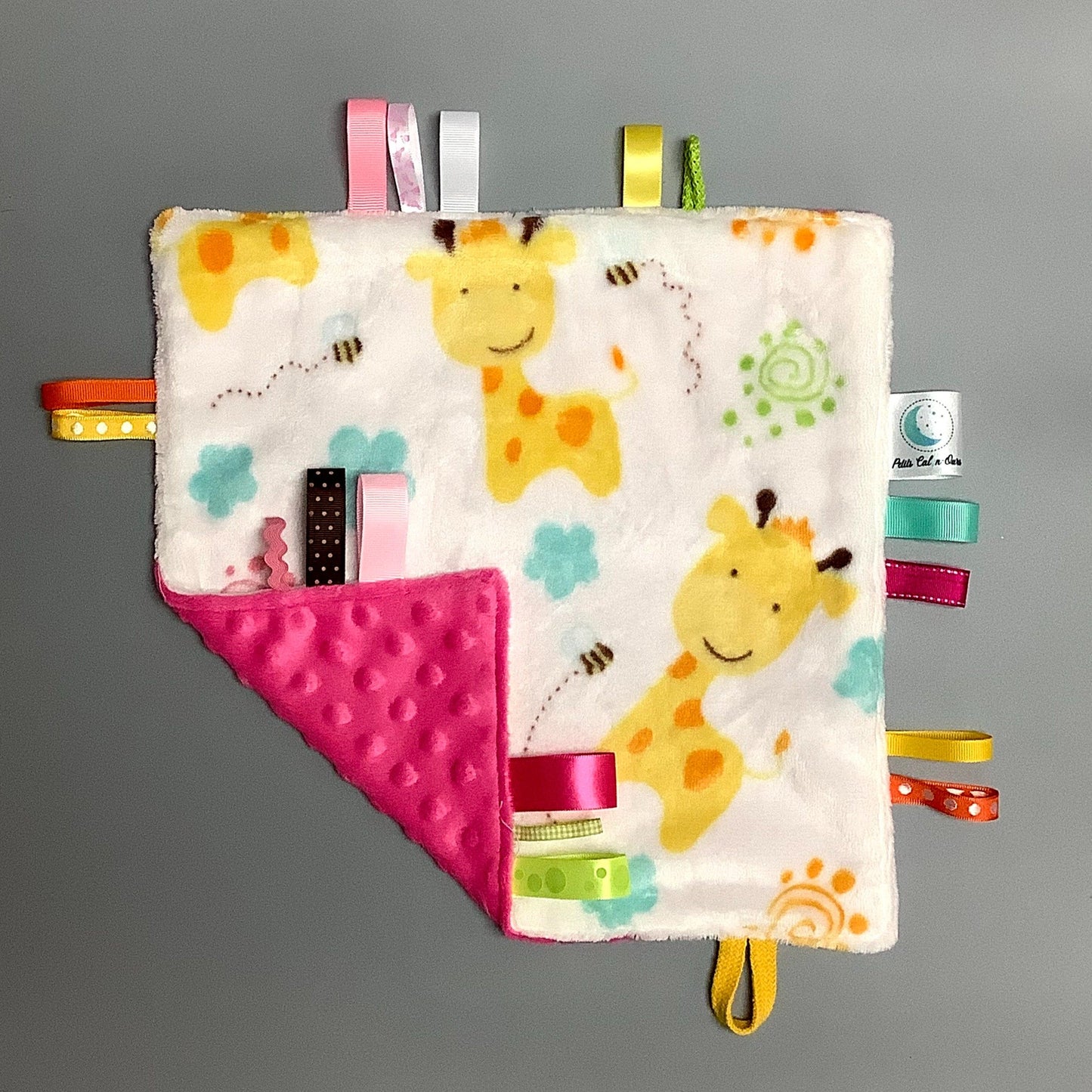 Doudou Calyn pour les enfants Fait en coton et avec du polars flanelle (notre tissu à doudou super doux), avec différents rubans. Chaque doudou est fait au Québec et est unique. Doudou : 12'' x 12''