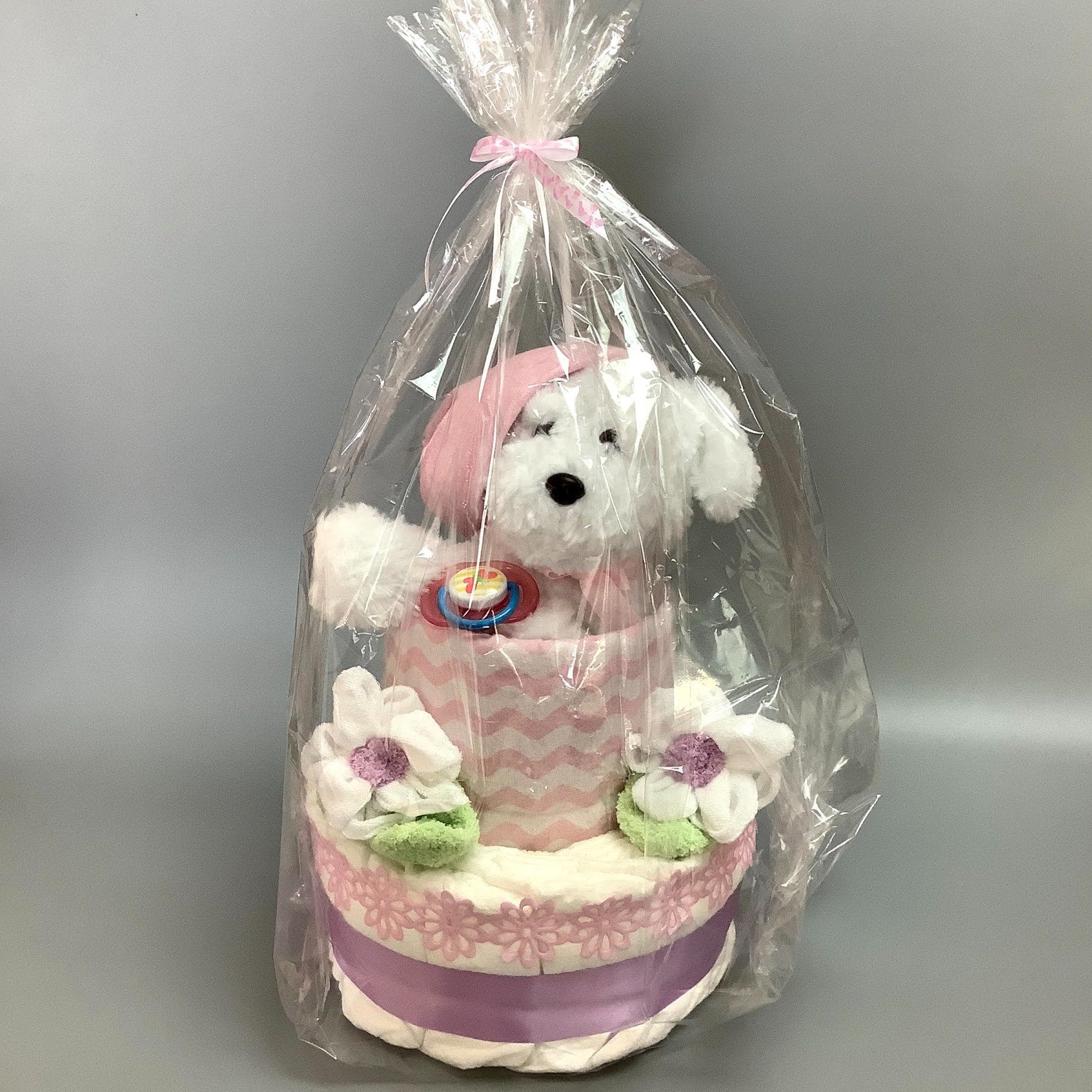 Ce gâteau contient :  - 12 couches (#2)  - 1 suce  - 1 toutou de chien   - 2 Débarbouillettes  - 2 paires de bas  - 1 doudou en flannelette  - 1 bonnet  Ce produit est unique et fait ici au Québec