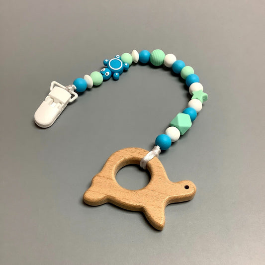Jouet de dentition avec attache-suce fait avec plusieurs billes en silicones de différentes couleurs, tailles et formes, et il est complété par une attache en plastique