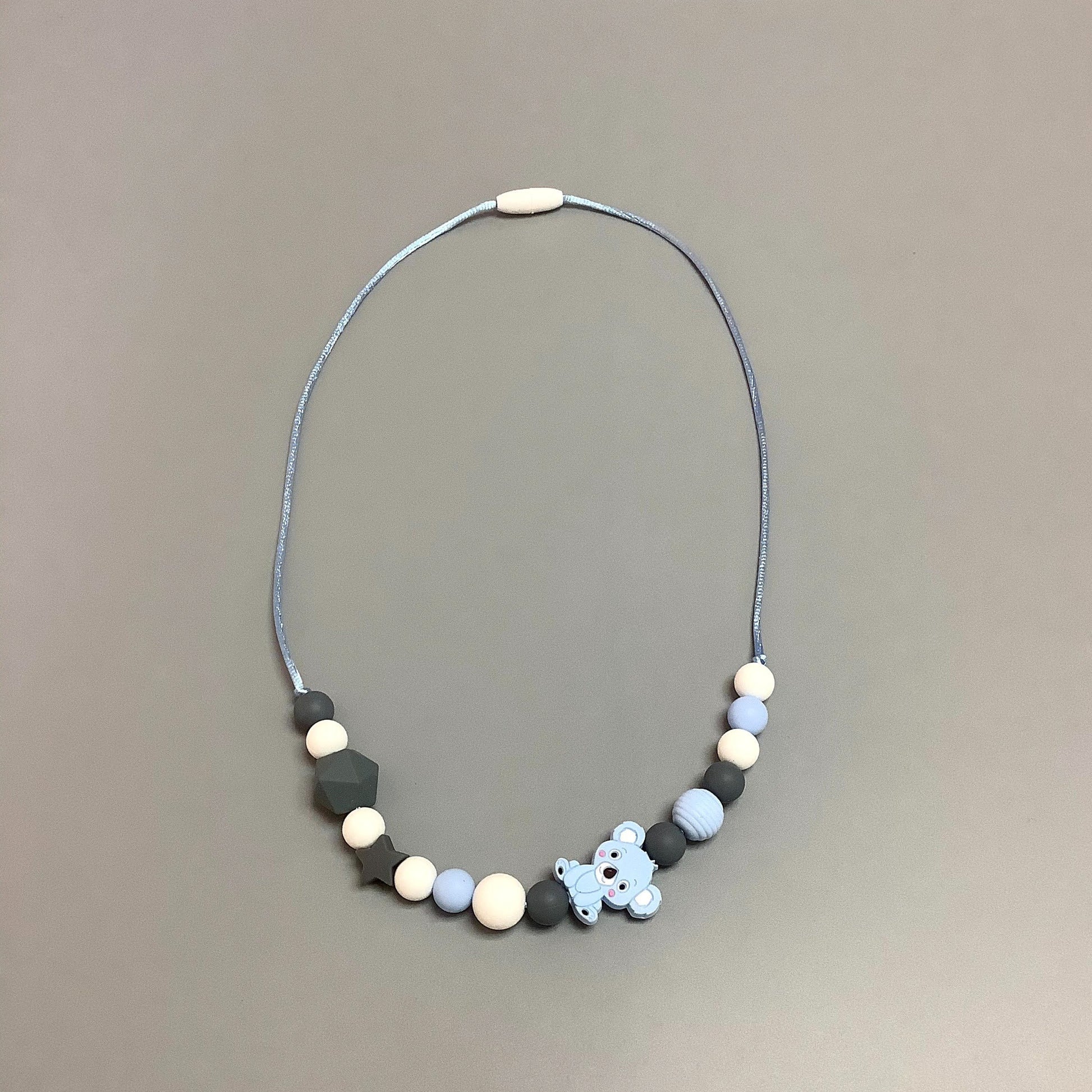 Collier en silicone fait avec plusieurs billes en silicones de différentes couleurs, tailles et formes, et il est complété par une attache en plastique