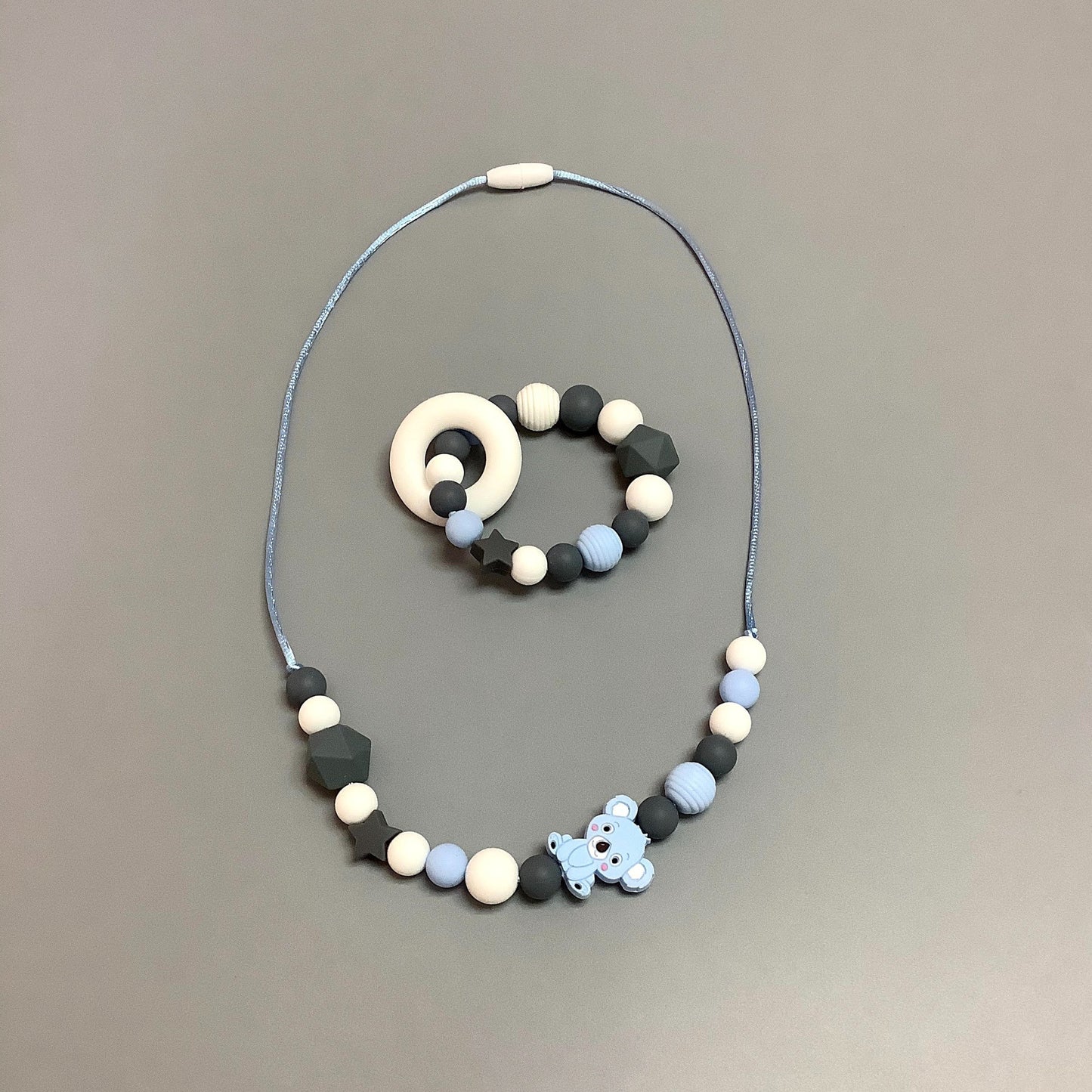 Collier en silicone fait avec plusieurs billes en silicones de différentes couleurs, tailles et formes, et il est complété par une attache en plastique.   Hochet d'éveil en silicone fait avec plusieurs billes en silicones de différentes couleurs et différentes tailles avec une plus gros jouet de dentition.