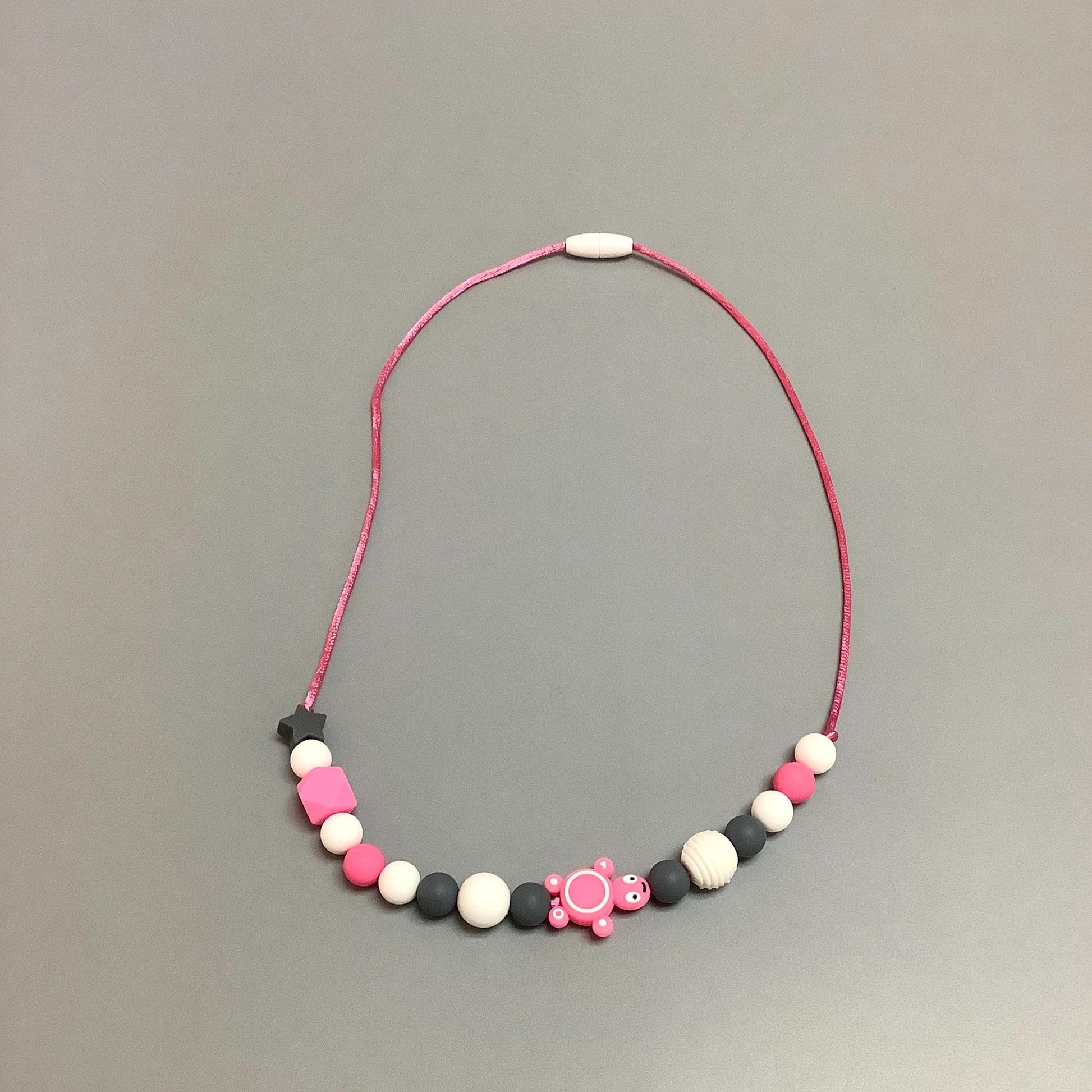 Collier en silicone fait avec plusieurs billes en silicones de différentes couleurs, tailles et formes, et il est complété par une attache en plastique.