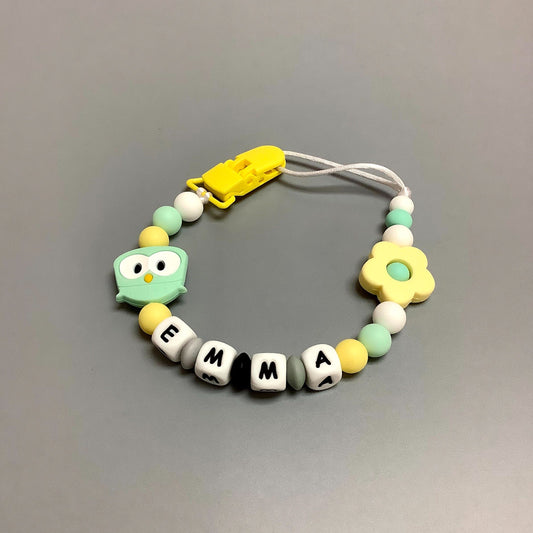 Jouet de dentition avec attache-suce fait avec plusieurs billes en silicones de différentes couleurs, tailles et formes, et il est complété par une attache en plastique