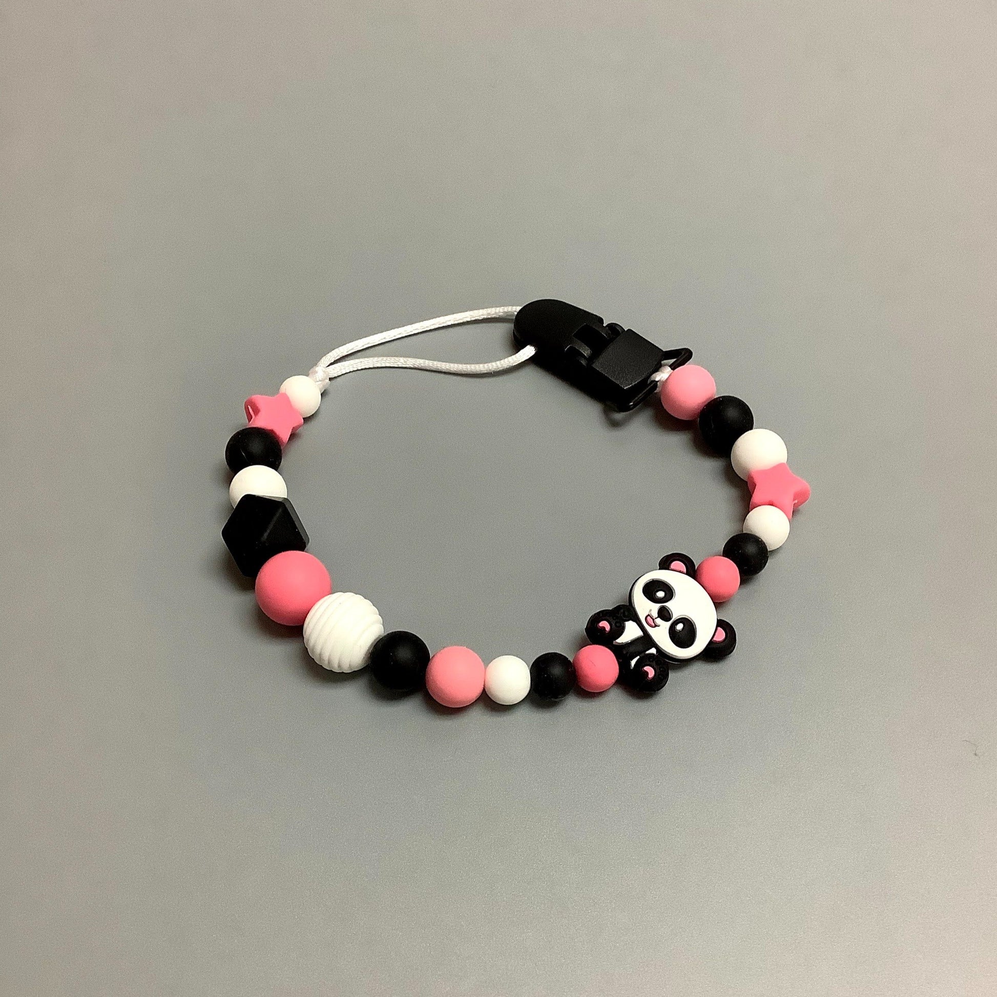 Jouet de dentition avec attache-suce fait avec plusieurs billes en silicones de différentes couleurs, tailles et formes, et il est complété par une attache en plastique.