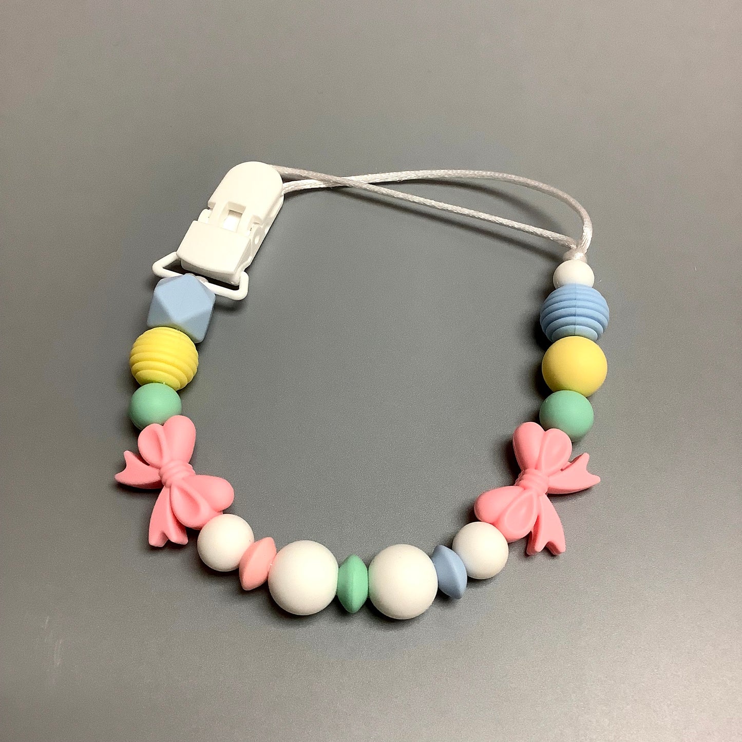 Attache-suce en silicone - Boucle rose et billes pastelles
