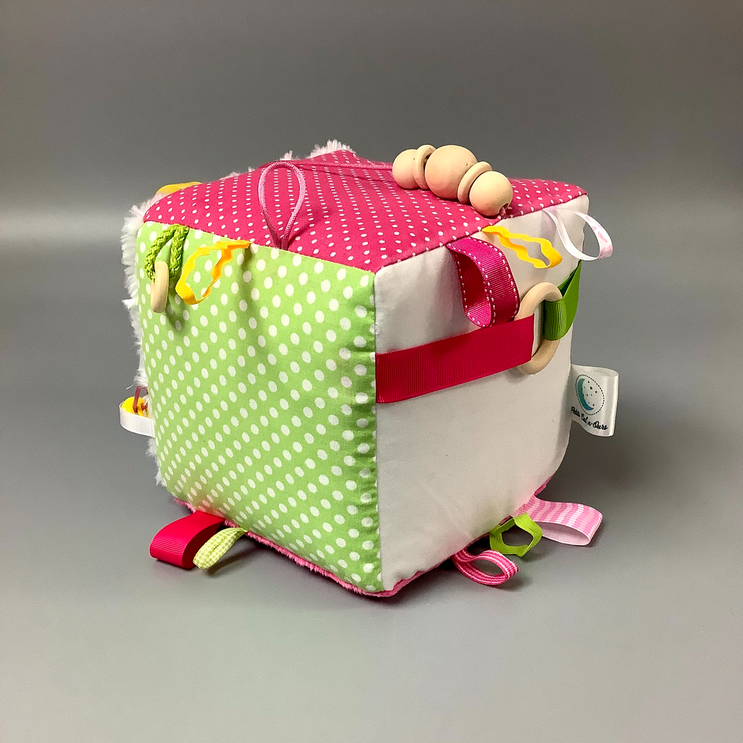 Cube d'éveil pour enfant  Fait en coton avec rubans et petits accessoires de bois. Le cube fait du bruit lorsqu'il est agité.  Ce produit unique est fait au Québec.
