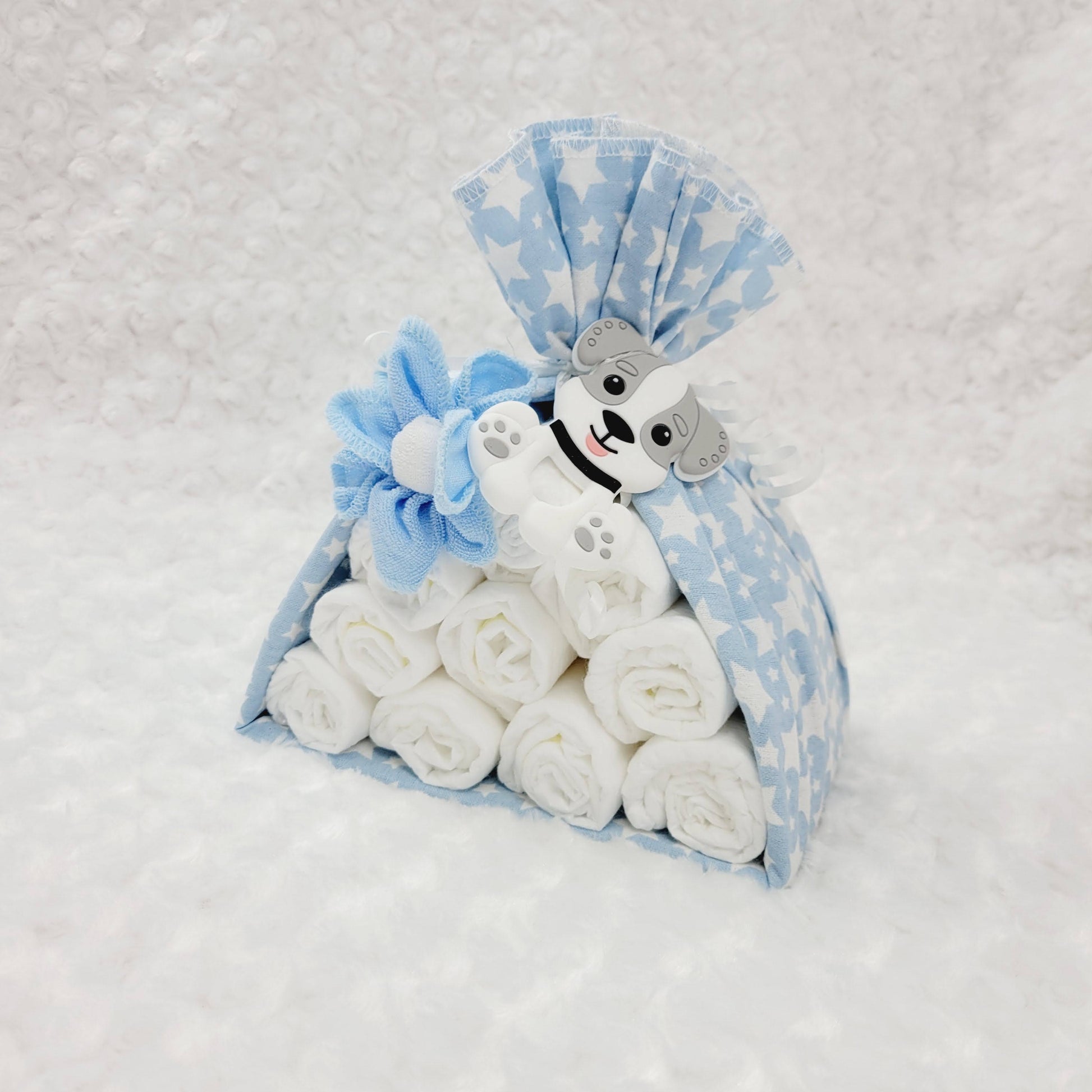 Baluchon avec couverture bleu étoilé blanc, contenant 10 couches de taille #2 avec une débarbouillettes bleu et une blanche. Complété d'un jouet de dentition en silicone en former de chien.