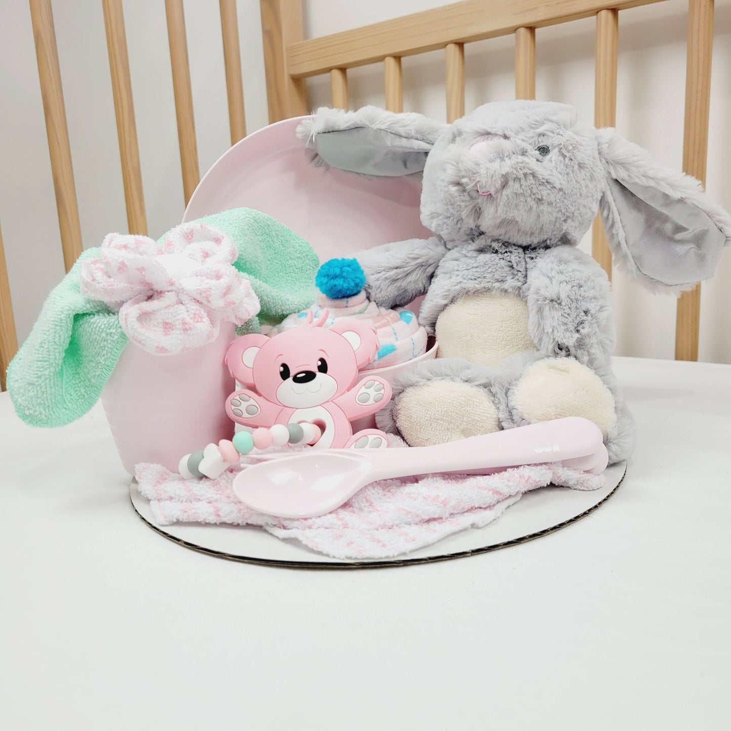 Ensemble cadeau de babyshower. Avec un toutou lapin gris, une couverture rose en flanelle. Complété d'une assiette, un bol et un verre rose avec des ustensiles pour enfant.  