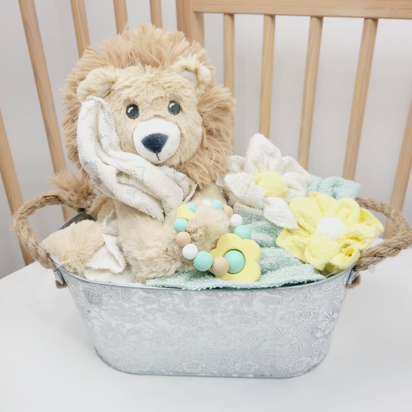 Ensemble cadeau pour babyshower, panier contenant des débarbouillettes en fleur, un toutou de lion avec un jouet de dentition en silicone.
