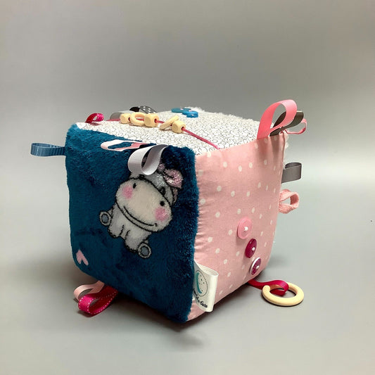 Cube d'éveil pour enfant  Fait en coton avec rubans et petits accessoires de bois. Le cube fait du bruit lorsqu'il est agité.  Ce produit unique est fait au Québec.