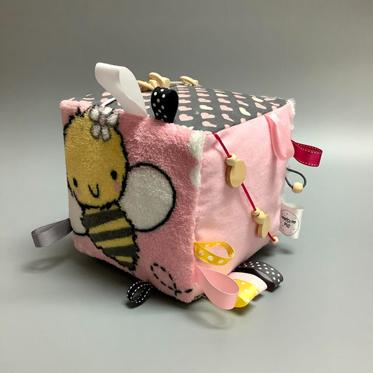 Cube d'éveil pour enfant  Fait en coton avec rubans et petits accessoires de bois. Le cube fait du bruit lorsqu'il est agité.  Ce produit unique est fait au Québec.