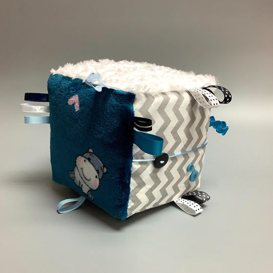 Cube d'éveil pour enfant  Fait en coton avec rubans et petits accessoires de bois. Le cube fait du bruit lorsqu'il est agité.  Ce produit unique est fait au Québec.