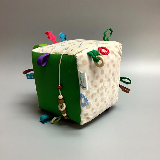 Cube d'éveil pour enfant  Fait en coton avec rubans et petits accessoires de bois. Le cube fait du bruit lorsqu'il est agité.  Ce produit unique est fait au Québec.