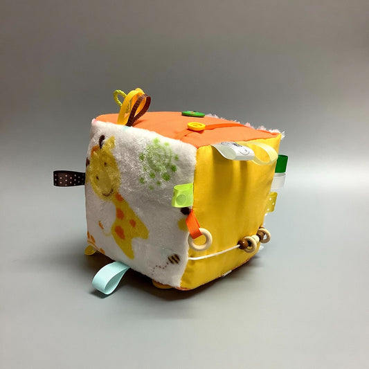 Cube d'éveil pour enfant  Fait en coton avec rubans et petits accessoires de bois. Le cube fait du bruit lorsqu'il est agité.  Ce produit unique est fait au Québec.