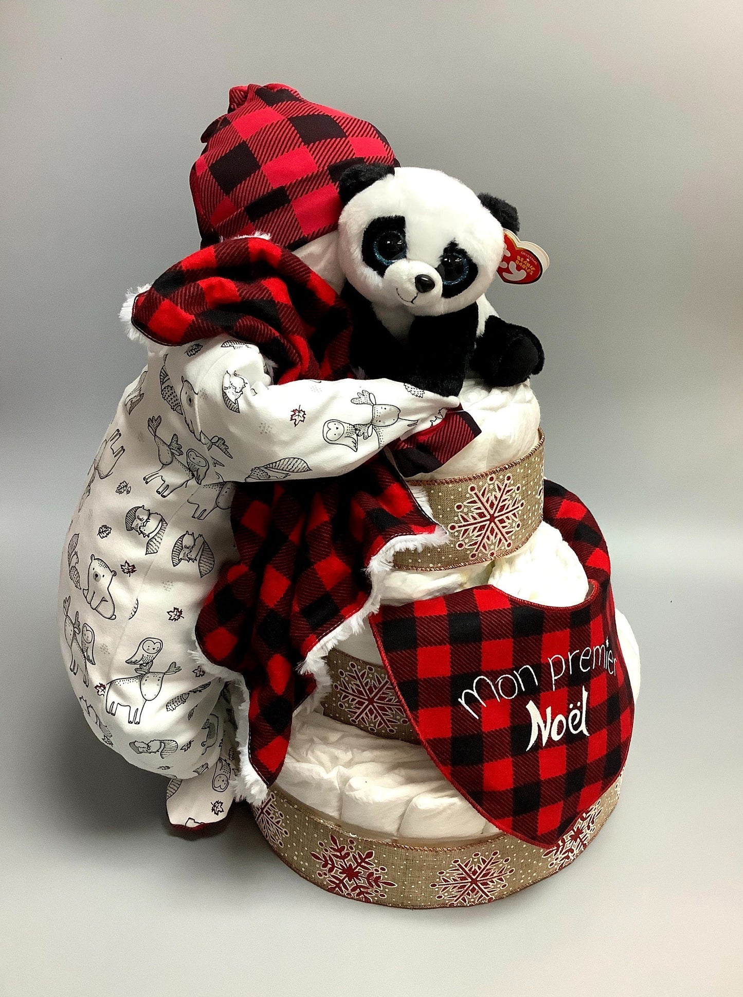 Ce gâteau contient :  - 60 couches (#2)  - 1 pyjamas - 1 bonnet en tricot de coton  - 1 toutou de panda  - 1 doudou 12'' x 12''  - 1 bavoir Mon premier Noël   Ce produit est unique et fait ici au Québec