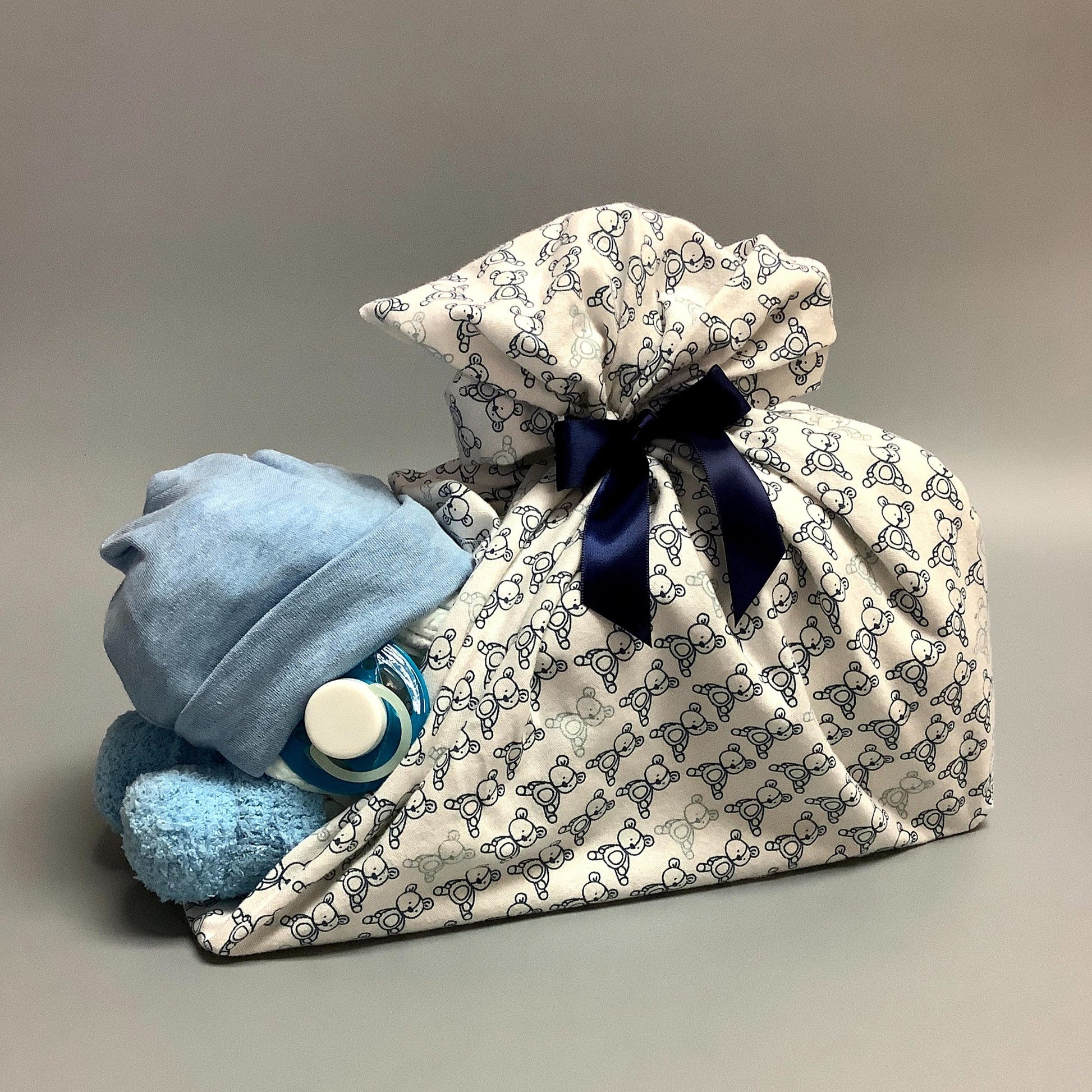 Ce panier contient :  - 16 couches (#2)  - 1 paires de bas   - 1 doudou en flannelette (30'' x 30'')  - 1 bonnet en tricot de coton   - 1 suce    Ce produit est unique et fait ici au Québec