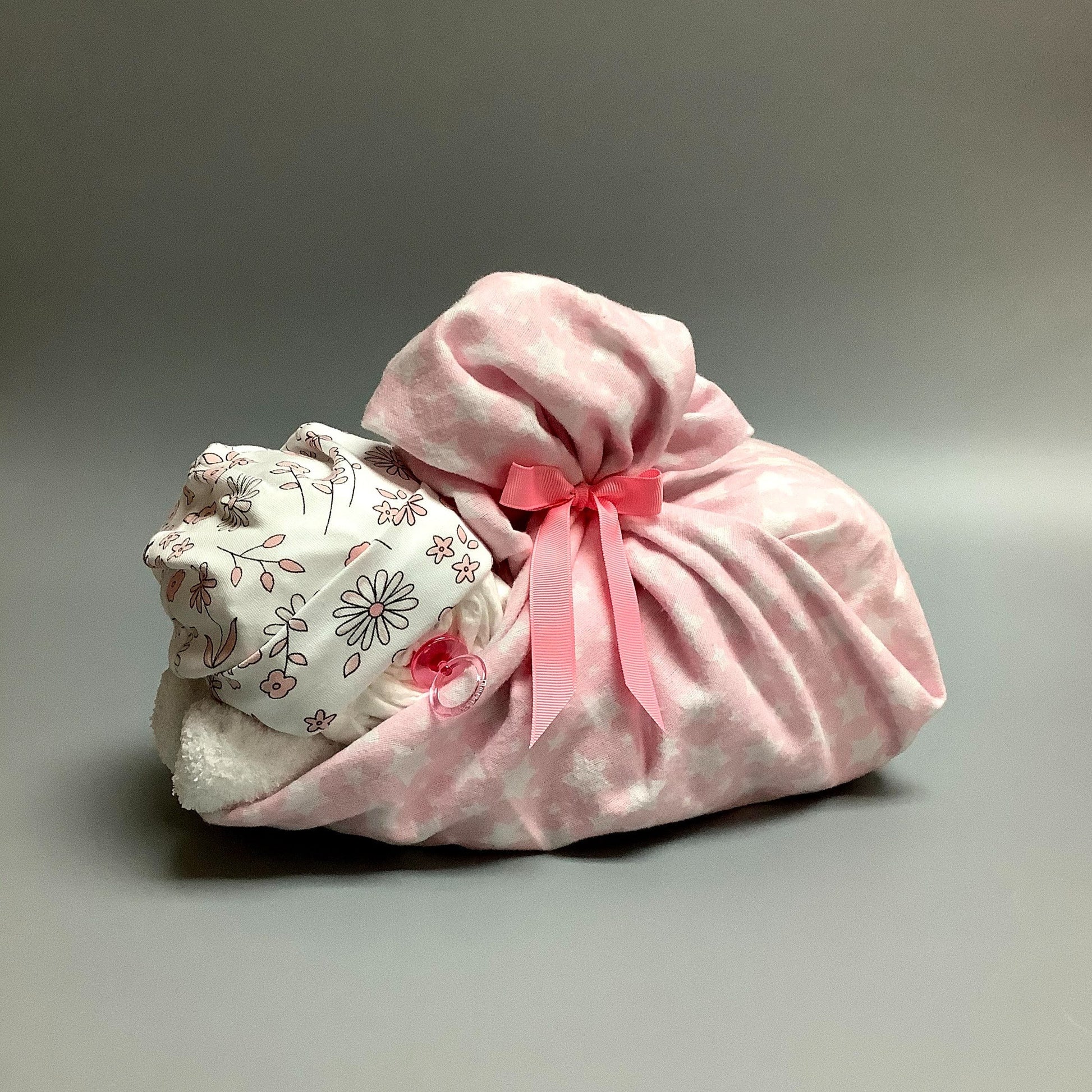 Ce panier contient :  - 16 couches (#2)  - 1 paires de bas   - 1 doudou en flannelette (30'' x 30'')  - 1 bonnet en tricot de coton   - 1 suce    Ce produit est unique et fait ici au Québec