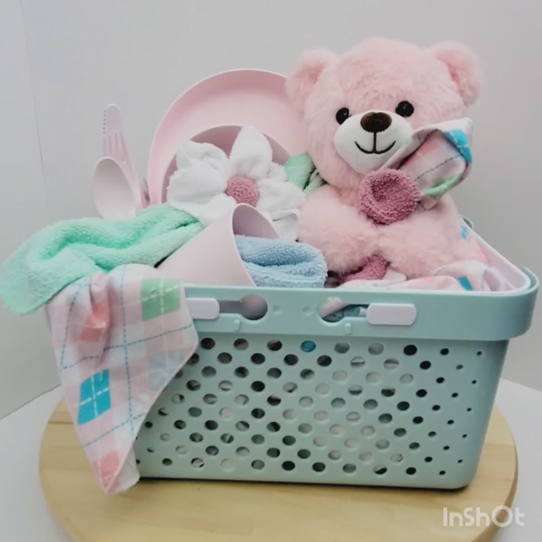 Vidéo 360 de l'Ensemble cadeau pour babyshower pour bébé fille. Un panier turquoise rempli d'une couverture rose en flanelle avec des débarbouillettes, un toutou ourson rose et en ensemble d'assiette, bol, verre et ustensile rose.