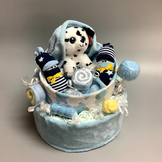 Ce gâteau contient :  - 15 couches (#2)  - 4 paires de bas  - 3 débarbouillettes (8''x8'')  - 1 doudou en flannelette avec des éléphants (30''x30'')  - 1 doudou en polars bleu (50''x34'')  - 1 toutou de chien   Ce produit est unique et fait ici au Québec,