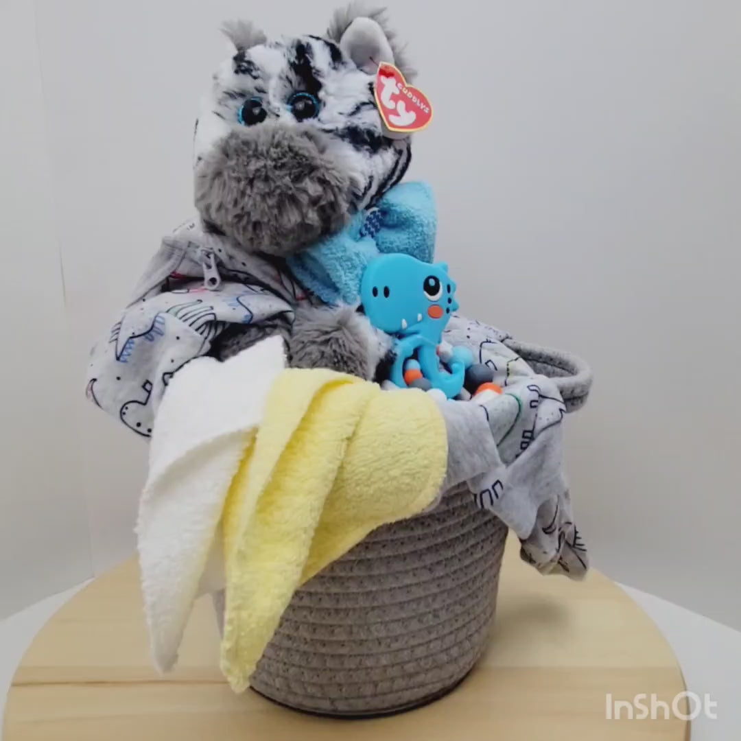 Vidéo 360 de l'Ensemble cadeau pour babyshower pour bébé. Dans un panier gris on retrouve un toutou zèbre avec un pyjama gris avec des dinosaures, un jouet de dentition avec un dino bleu.